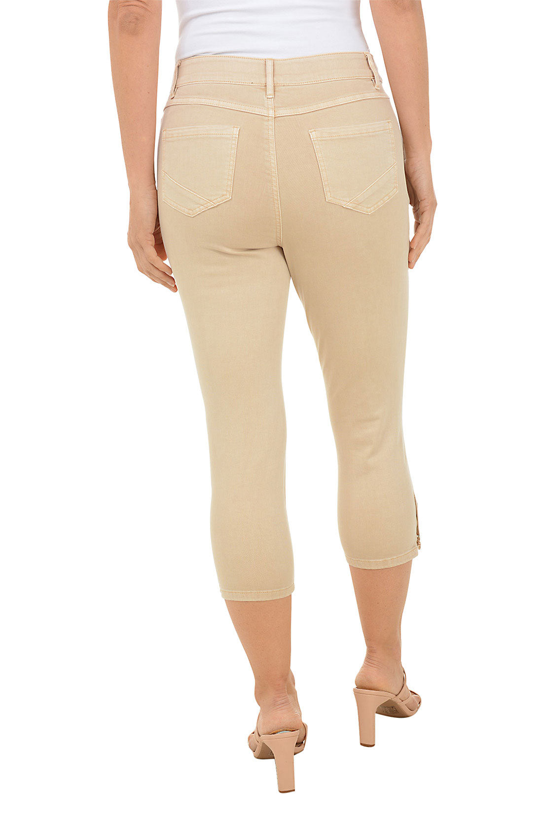A back shot of a model wearing a pair of beige denim capri pants with a stretch waistband, belt loops, dual front pockets, and triple studded detail on the hemline.