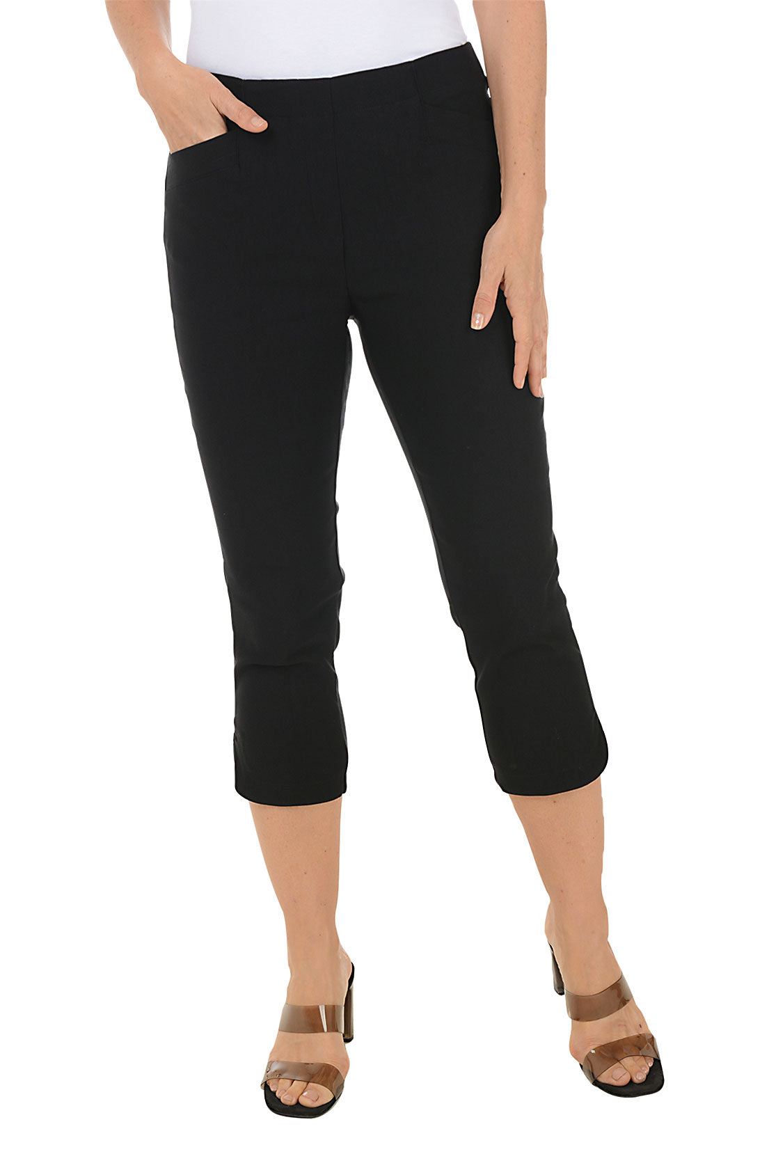 A front shot of a model wearing a pair of black capri pants with a stretch waistband and tummy control lining, featuring dual front pockets and a tulip hemline.