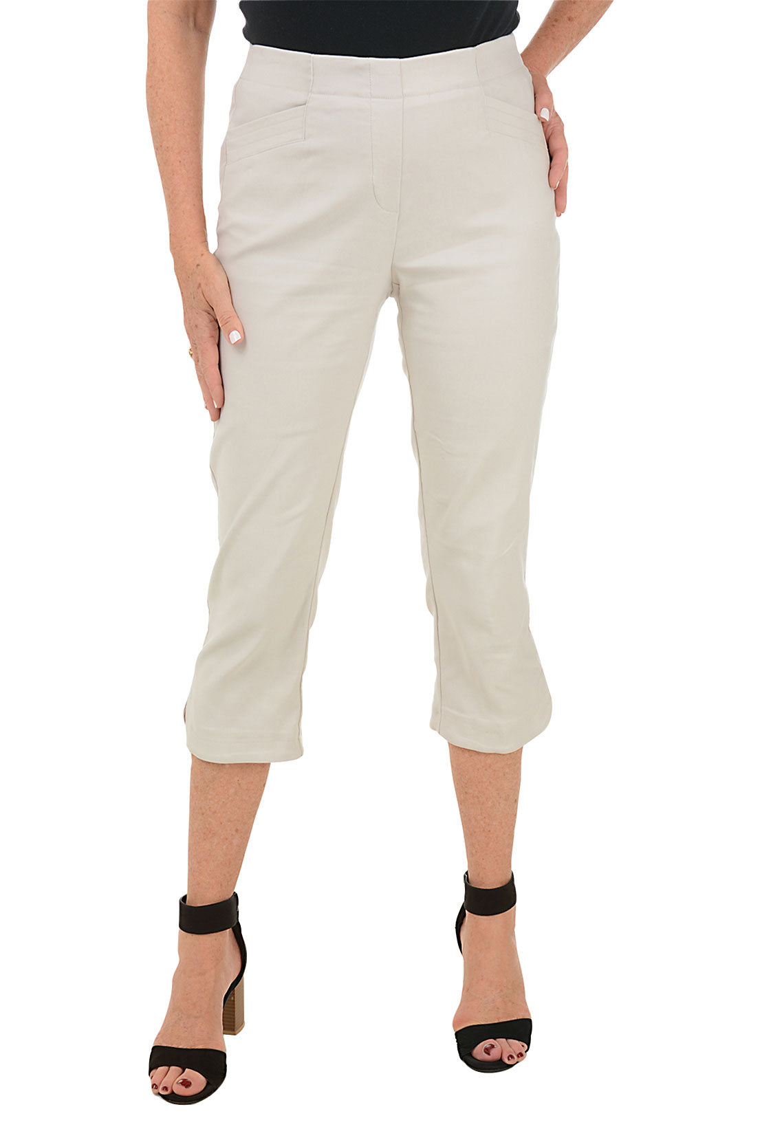 A front shot of a model wearing a pair of khaki capri pants with a stretch waistband and tummy control lining, featuring dual front pockets and a tulip hemline.