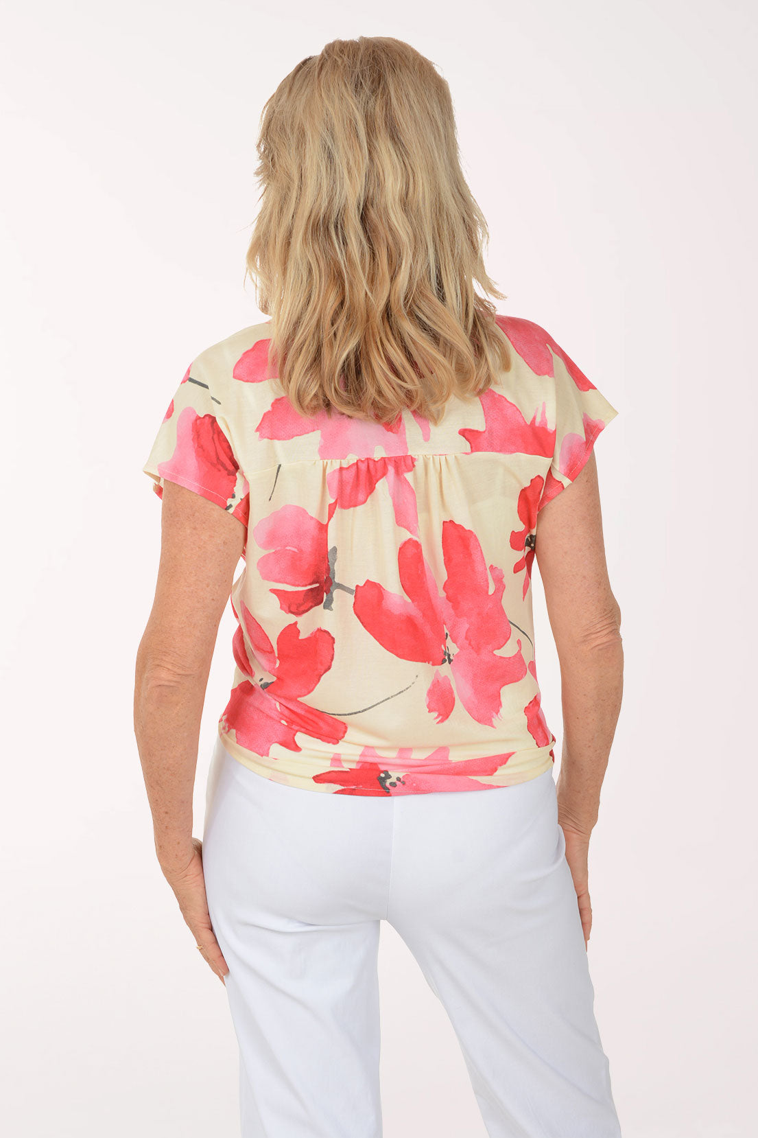 Woman wearing a floral blouse and white pants on a white background