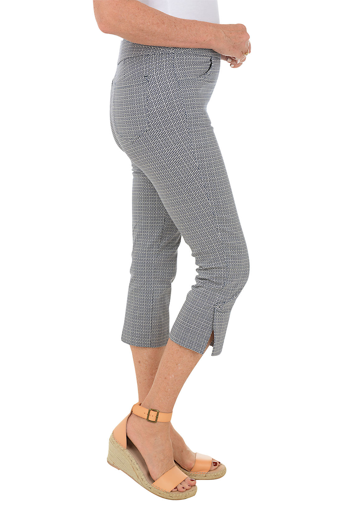 A side shot of a model wearing navy checkered capri pants with a stretch waistband, dual pockets, and button embellishment on the hem.