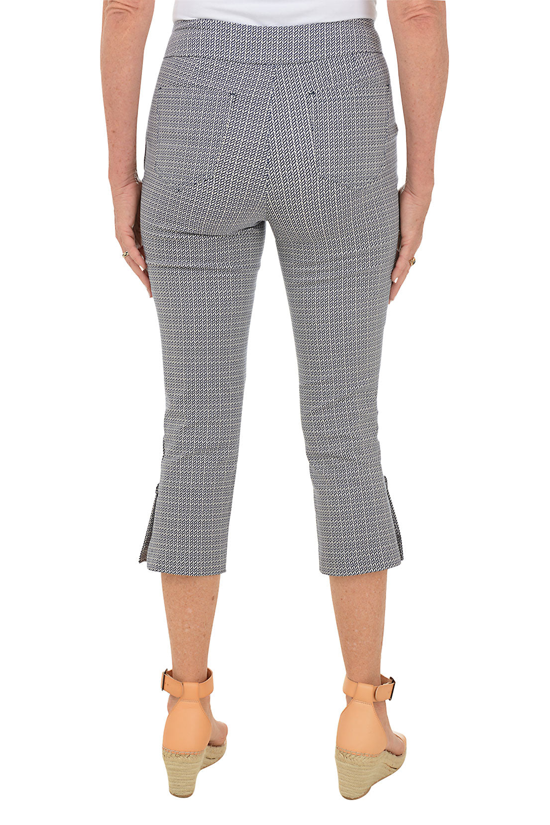 A back shot of a model wearing navy checkered capri pants with a stretch waistband, dual pockets, and button embellishment on the hem.