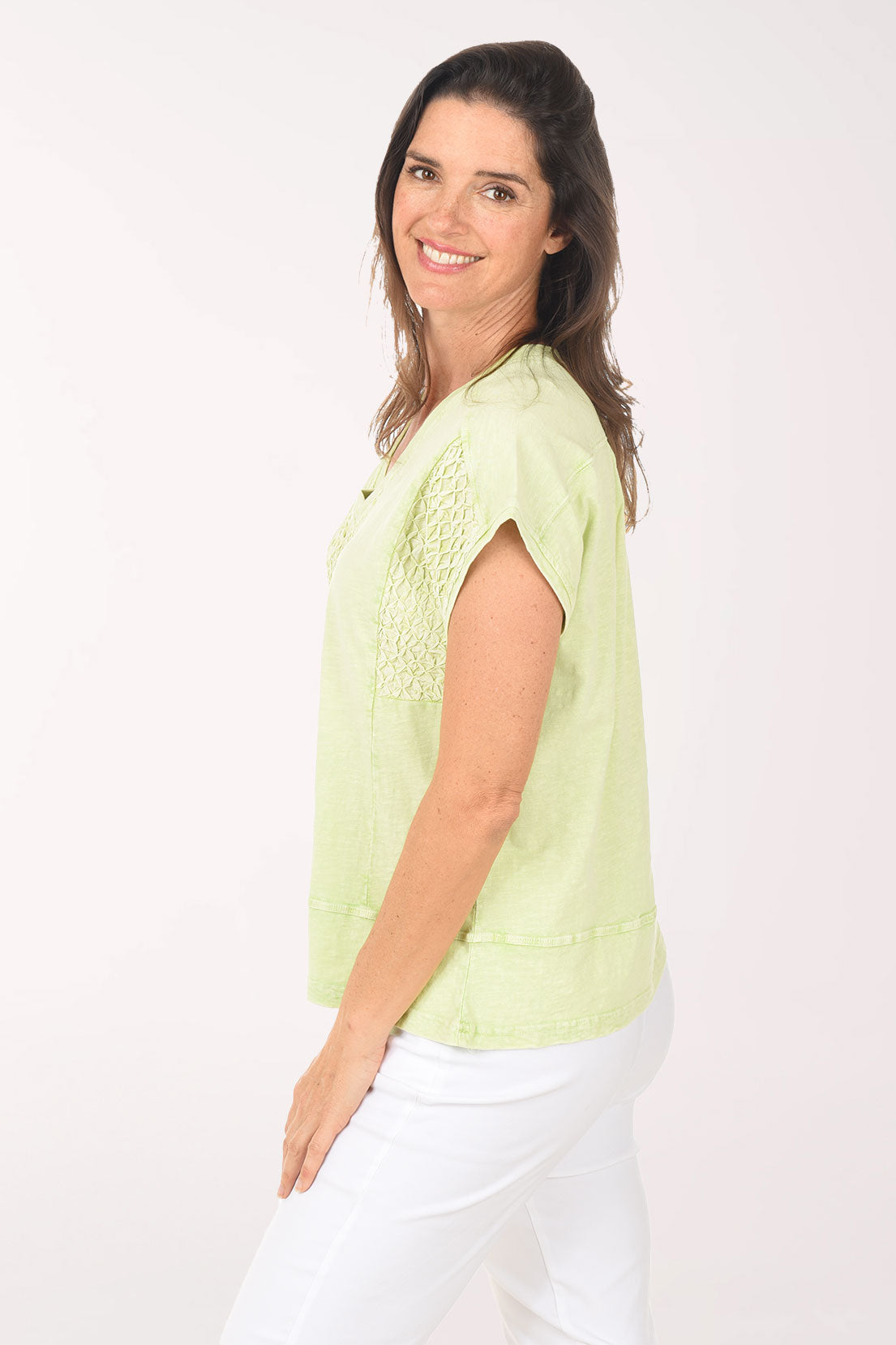 Woman wearing a light green blouse and white pants on a white background