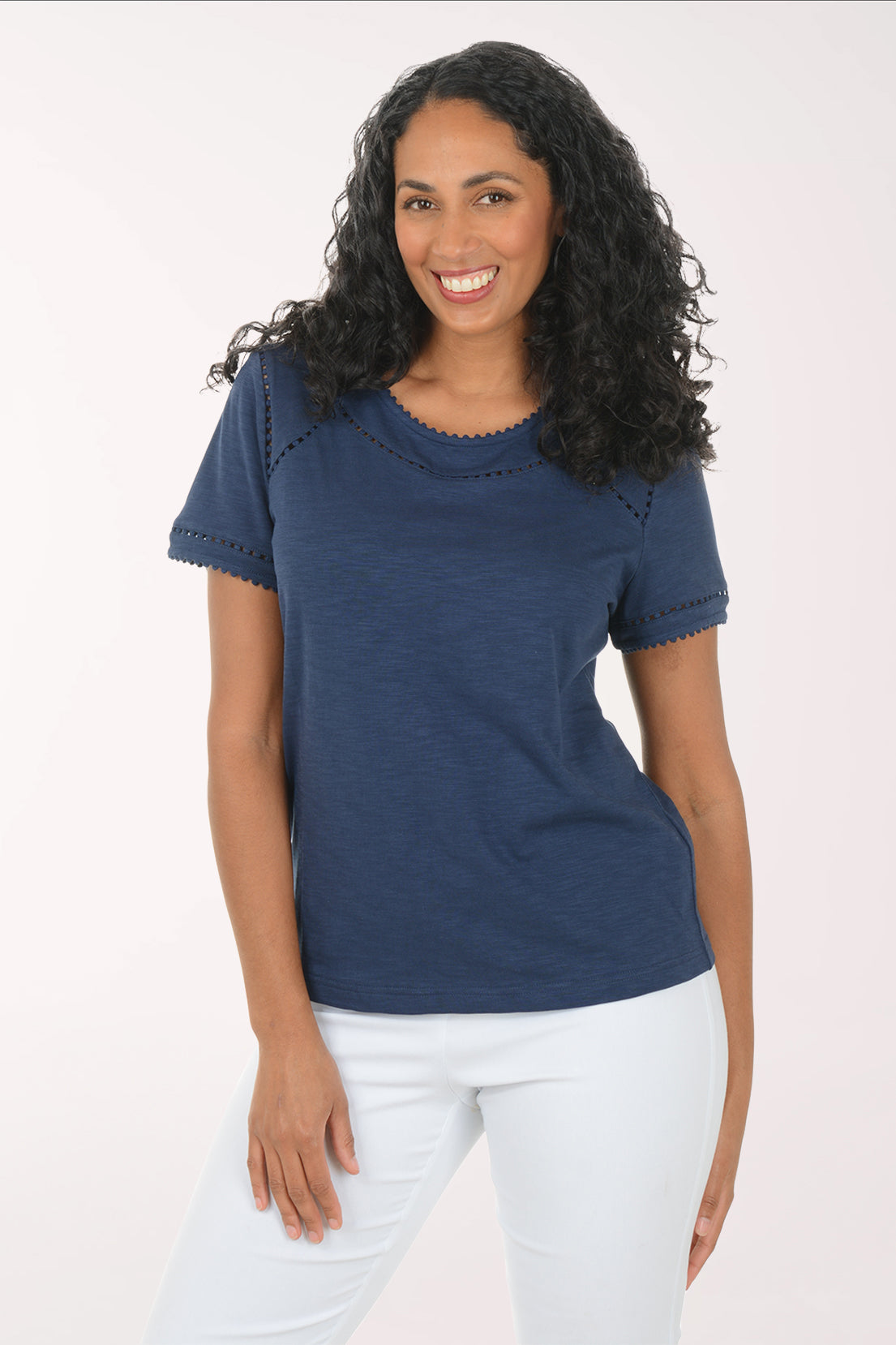 Woman wearing a blue top and white pants on a white background