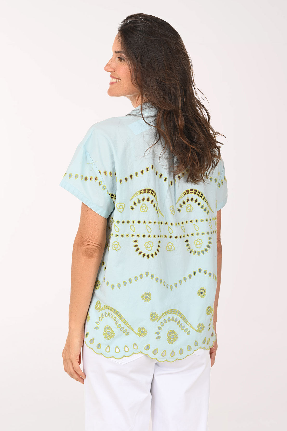 Woman wearing a light blue blouse with gold patterns on a white background
