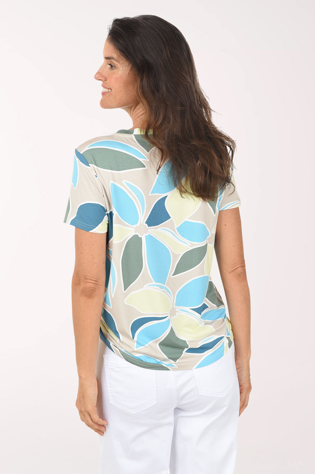 Woman wearing a colorful leaf-patterned top against a white background