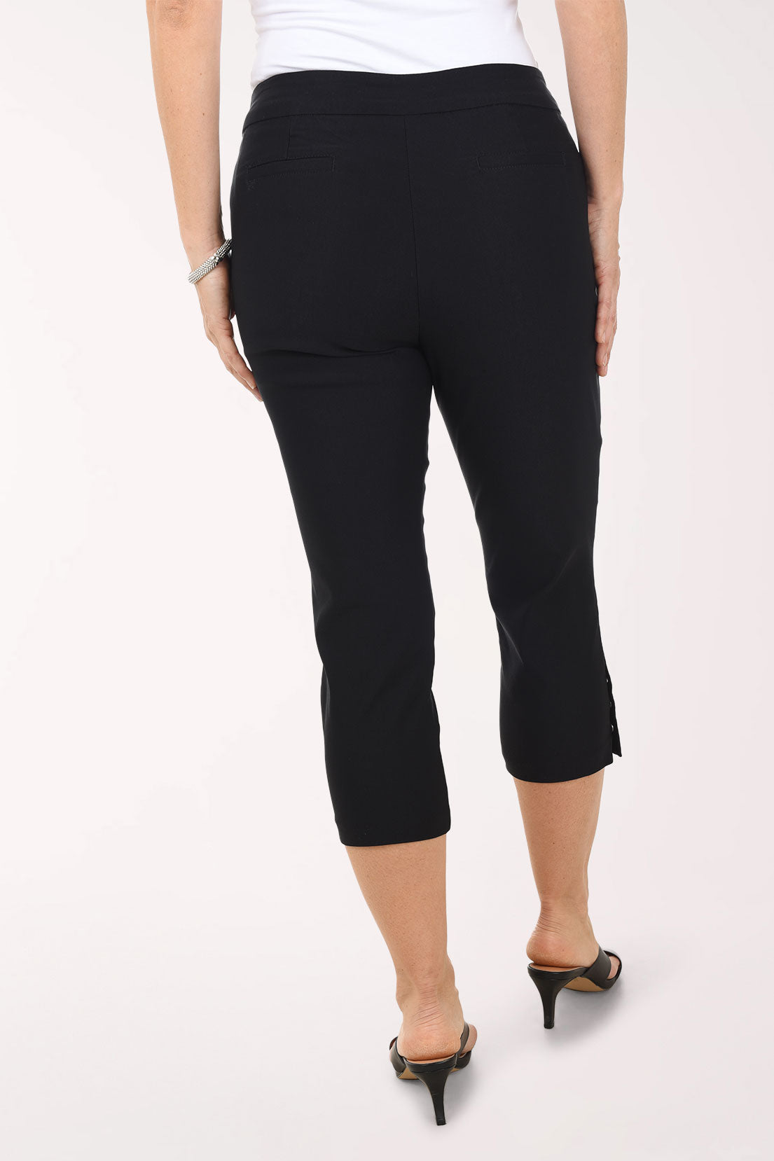 Person wearing black capri pants on a white background