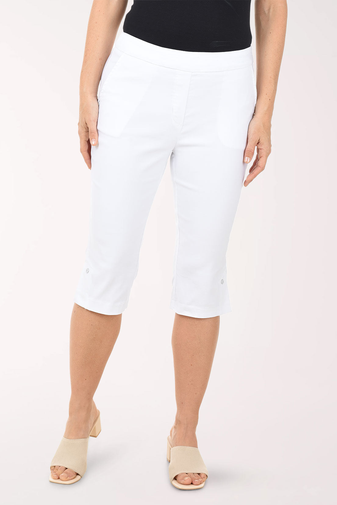 Person wearing white capri pants on a plain background