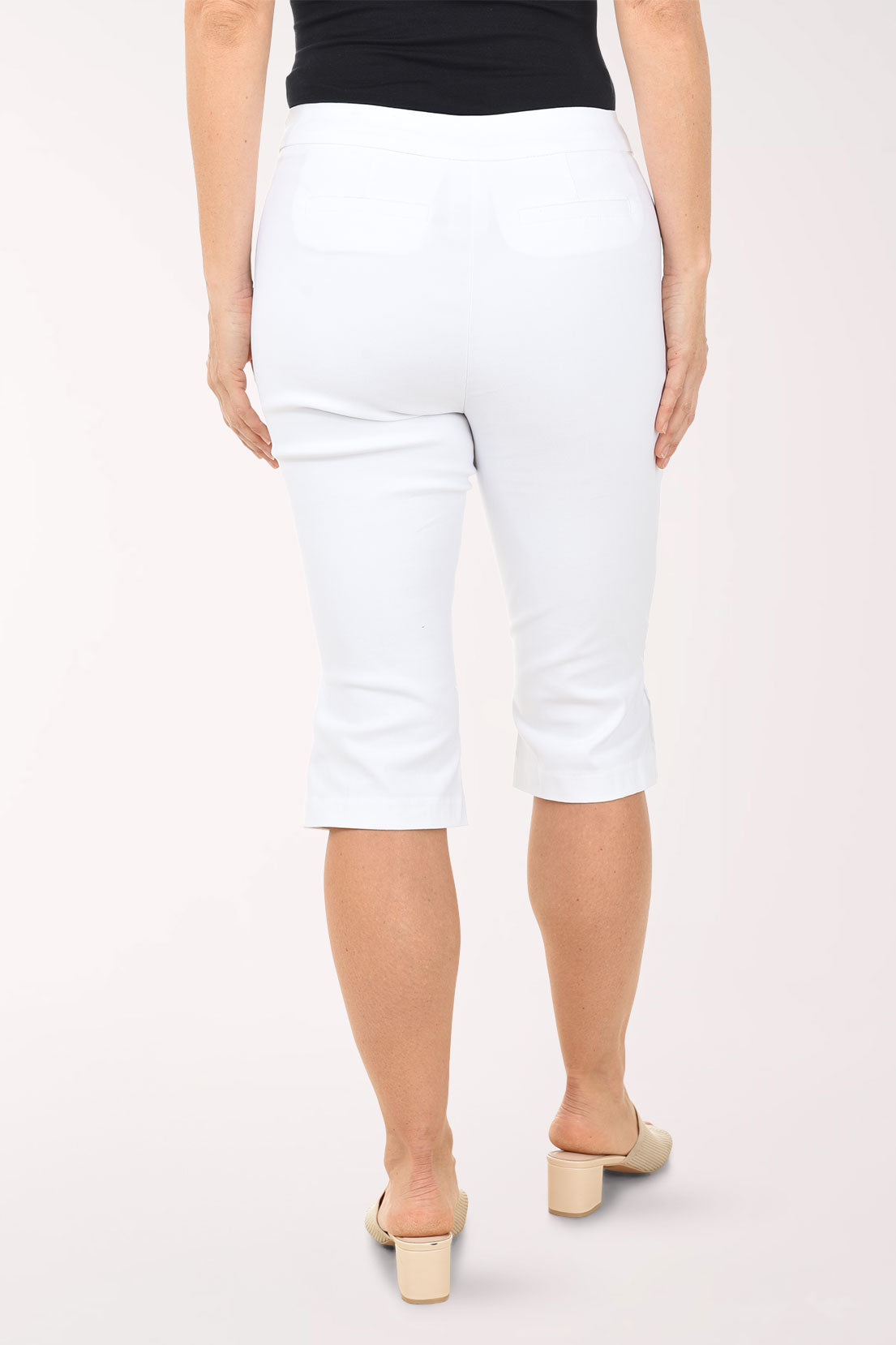 Person wearing white capri pants on a plain background