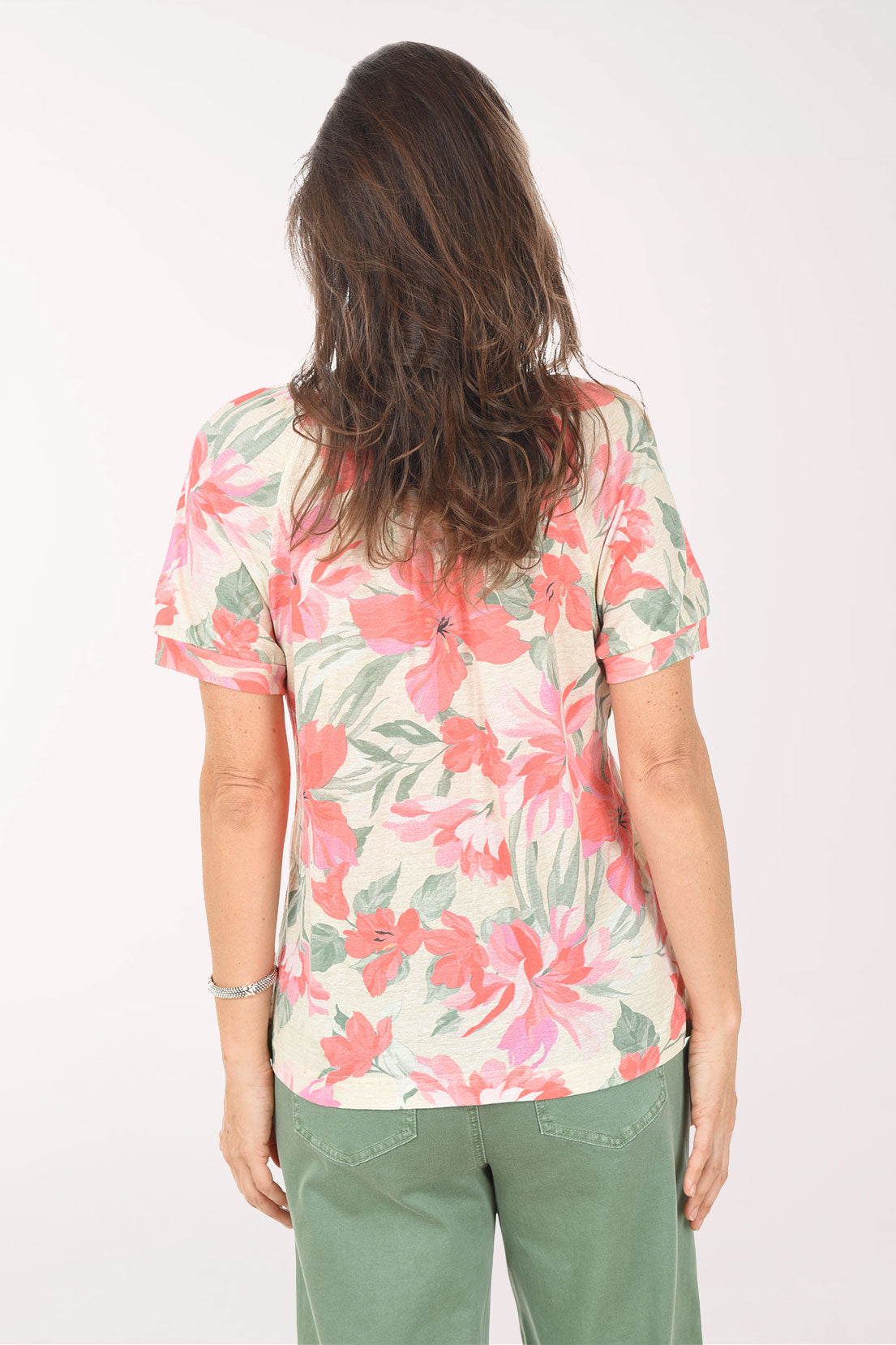 Woman wearing a floral blouse with pink and green colors on a white background