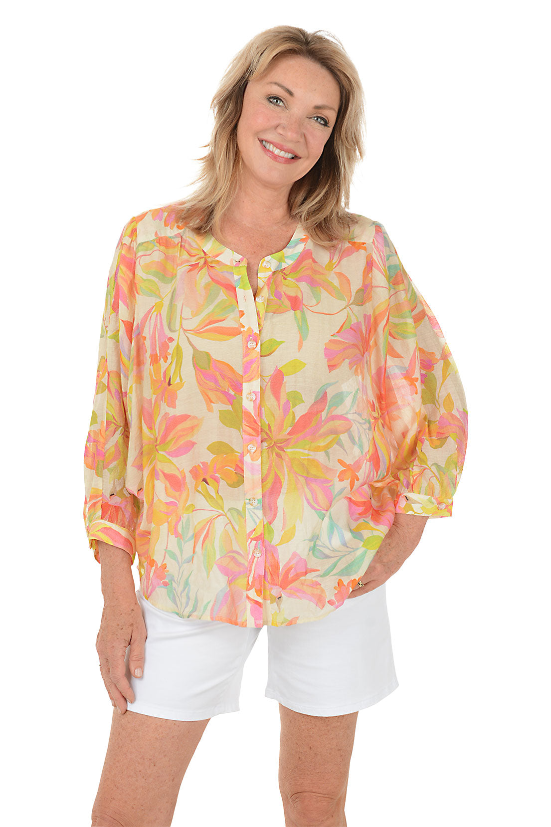 Woman wearing a colorful floral blouse and white shorts on a white background