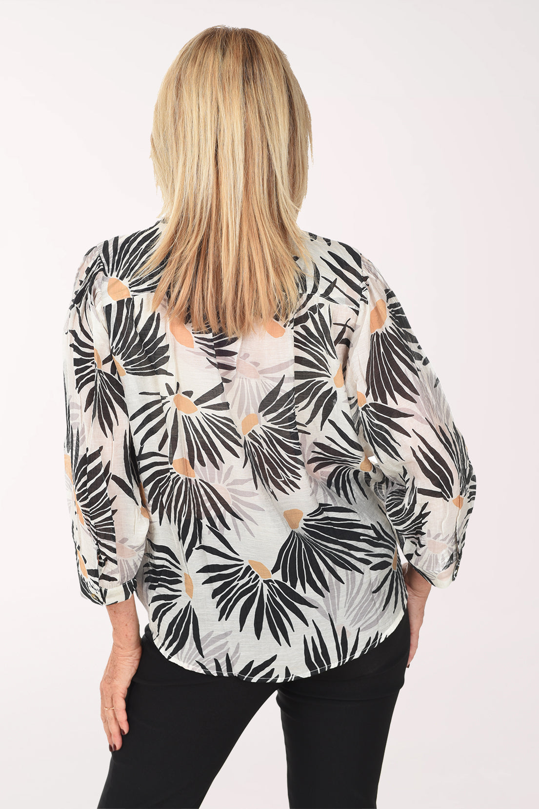 Woman wearing a tropical leaf patterned blouse on a white background