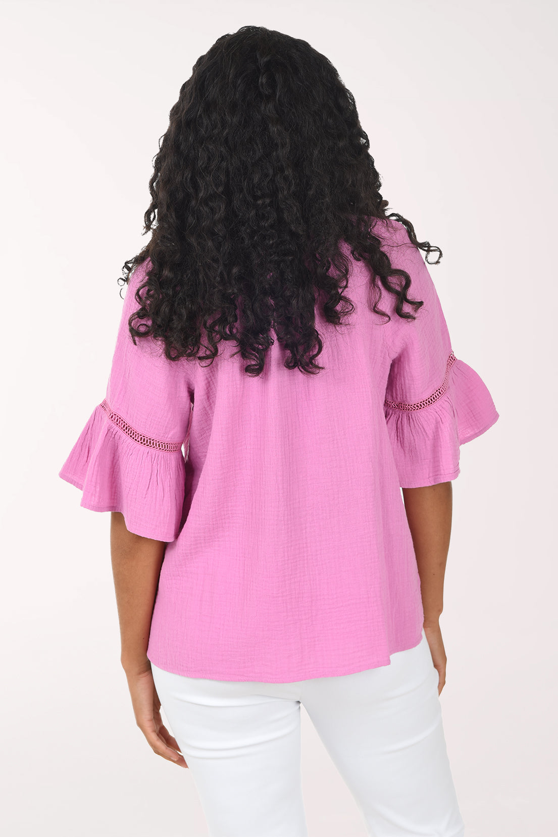 Woman wearing a pink blouse with ruffled sleeves on a white background