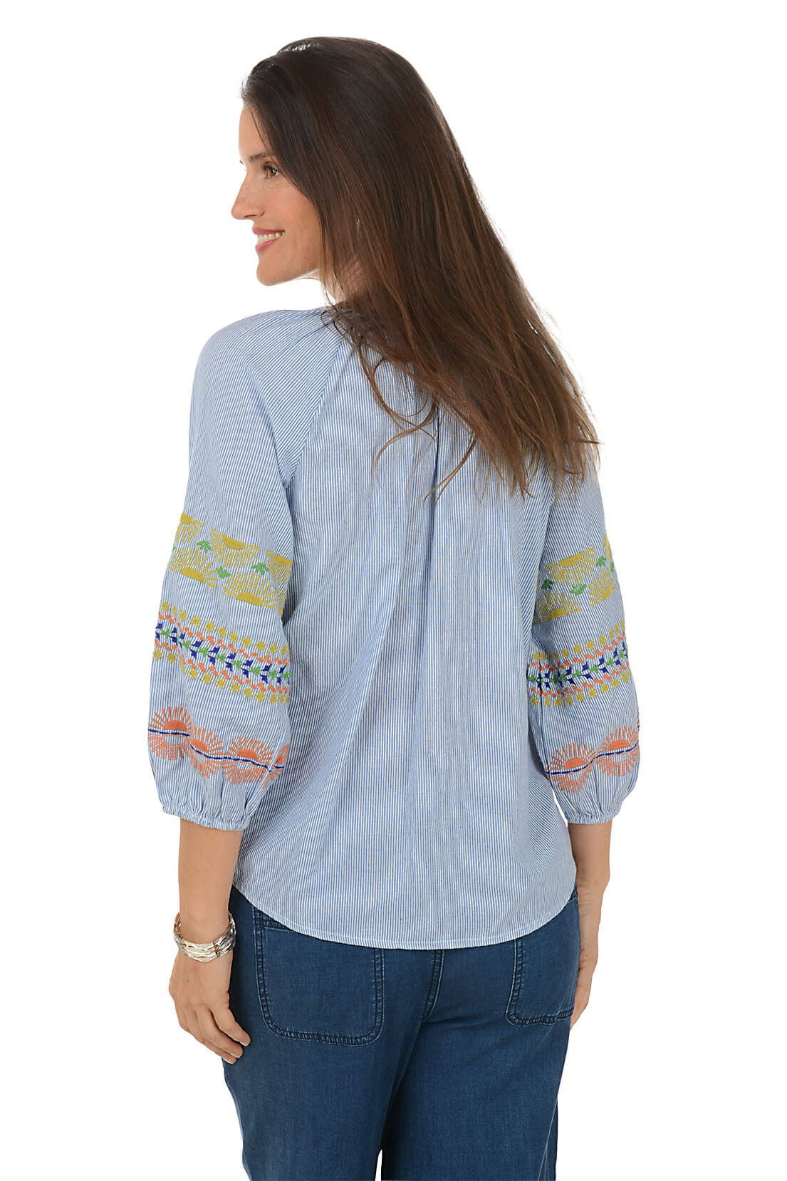 Woman wearing a light blue blouse with colorful patterns on the sleeves against a white background
