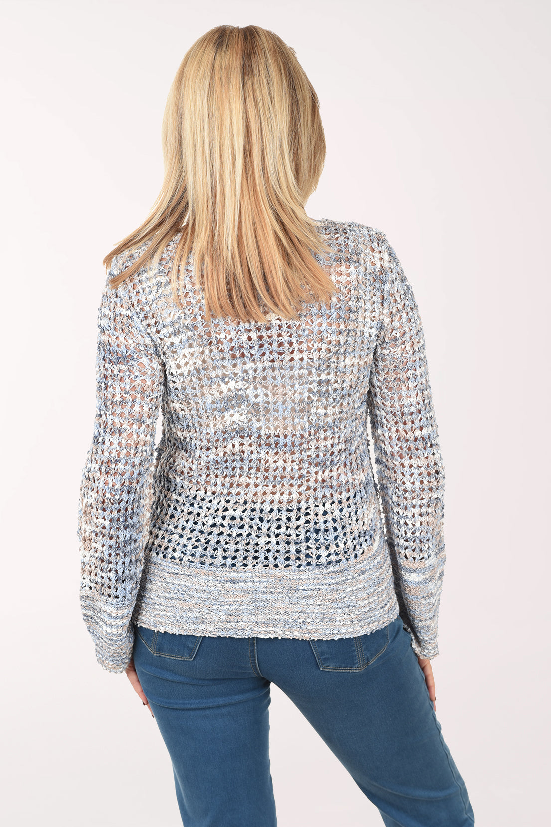 Woman wearing a textured sweater and blue jeans on a white background