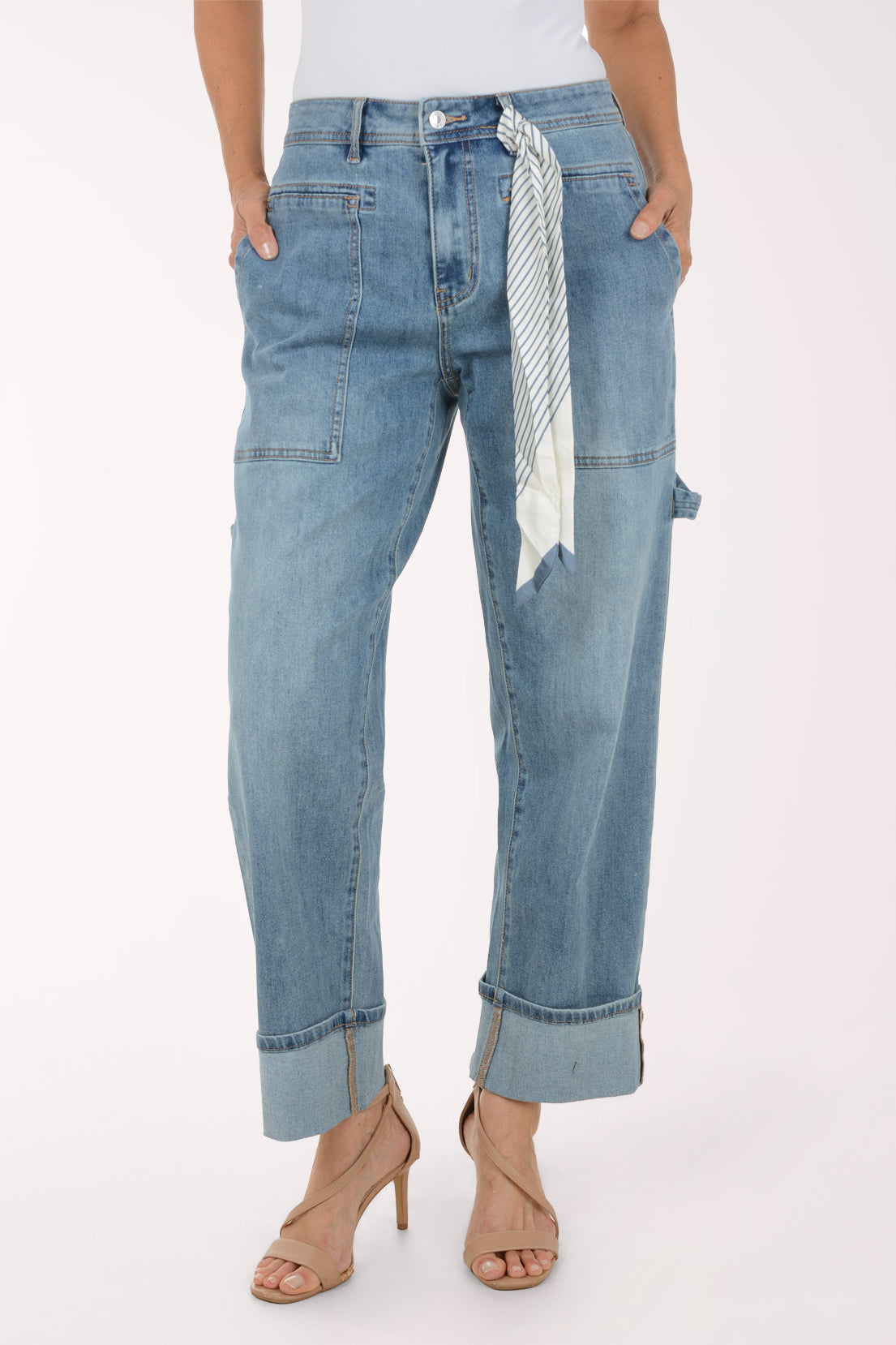 A model wearing light-wash blue denim jeans with a rolled cuff, side cargo pockets, and a striped fabric tie belt, paired with beige high-heeled sandals against a plain white background.