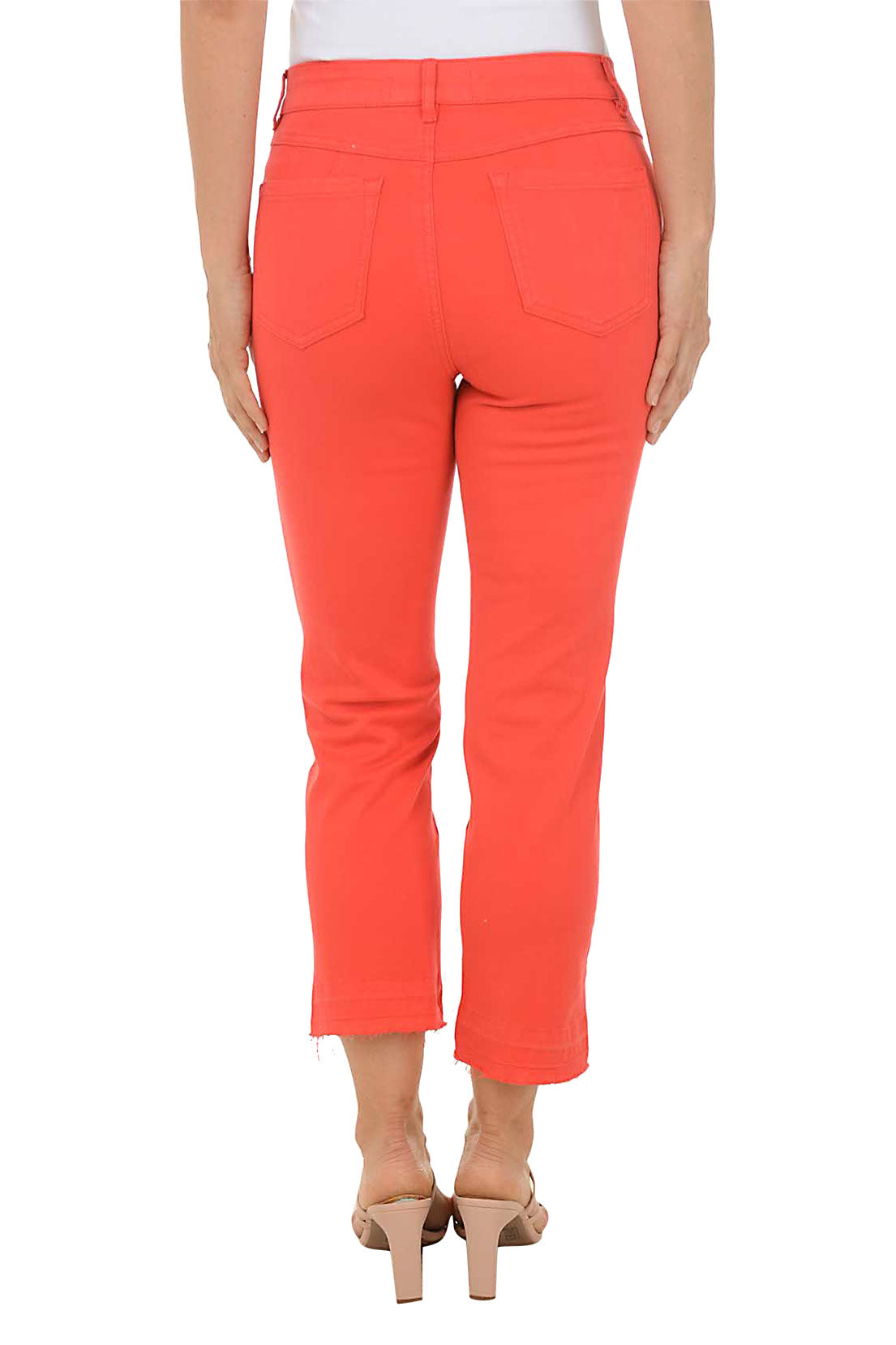 A back shot of a model wearing a pair of red distressed hem denim ankle pants with a belt loop, zip fly and button closure, and micro flared leg.