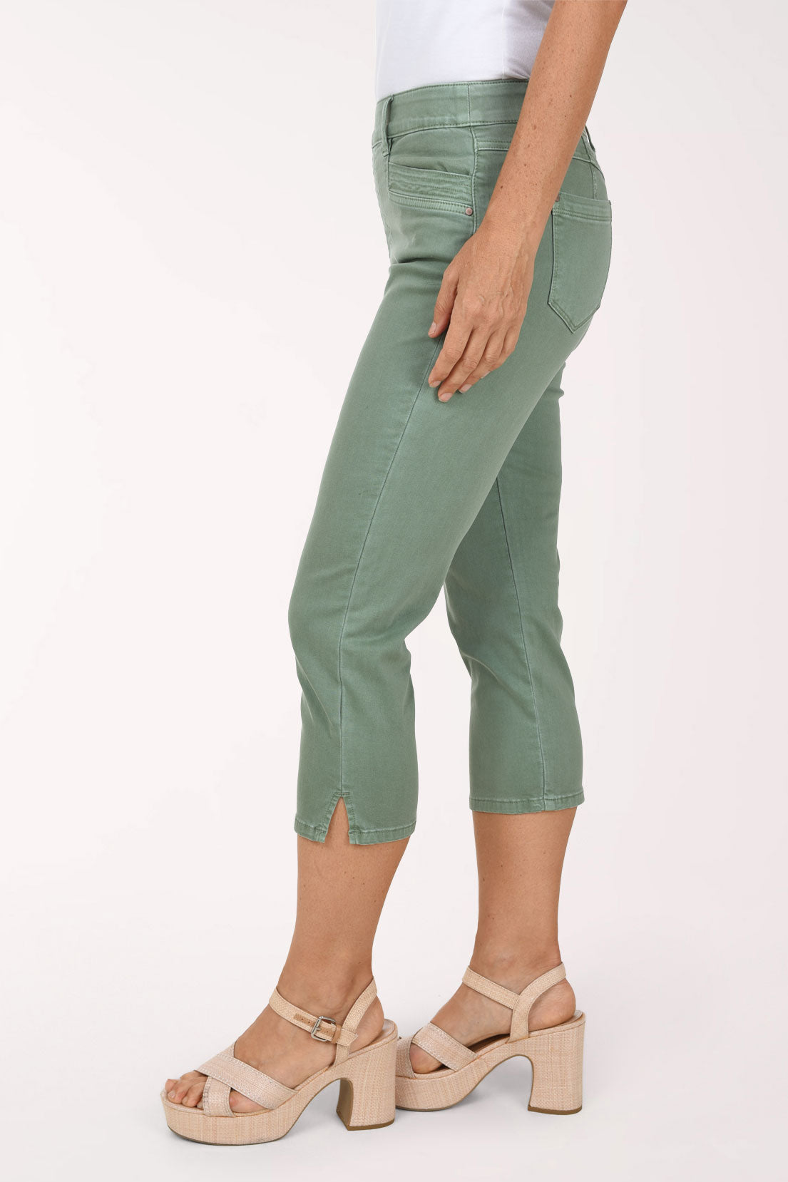 Side view of sage green Moss stretch denim capri pants showing the capri length below the knee and a small side slit at the hem.