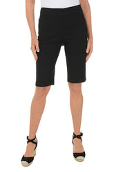 A model wearing black petite triple grommet hem bermuda shorts with elasticized waistband and dual front pockets.