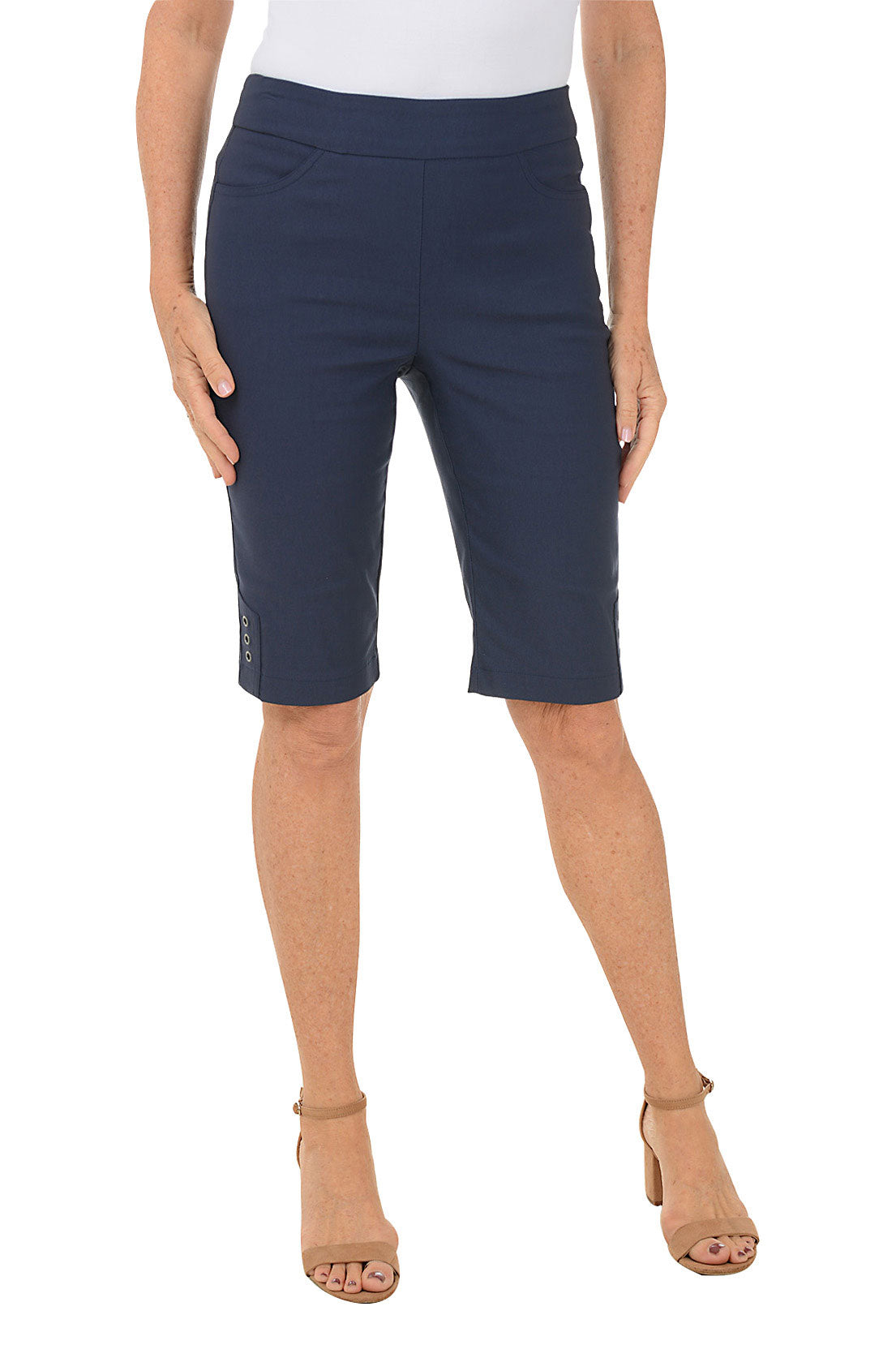 A model wearing navy petite triple grommet hem bermuda shorts with elasticized waistband and dual front pockets.