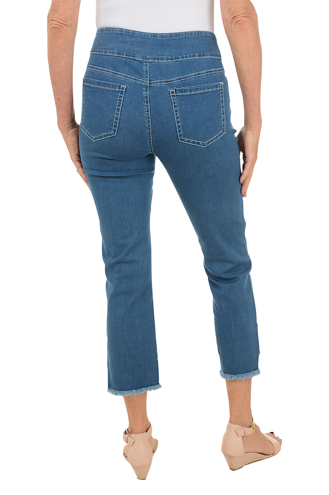 A pair of blue denim ankle pants with floral embroidery, a pull-on style with a 5-pocket design, and frayed hem with side slits. Back shot.