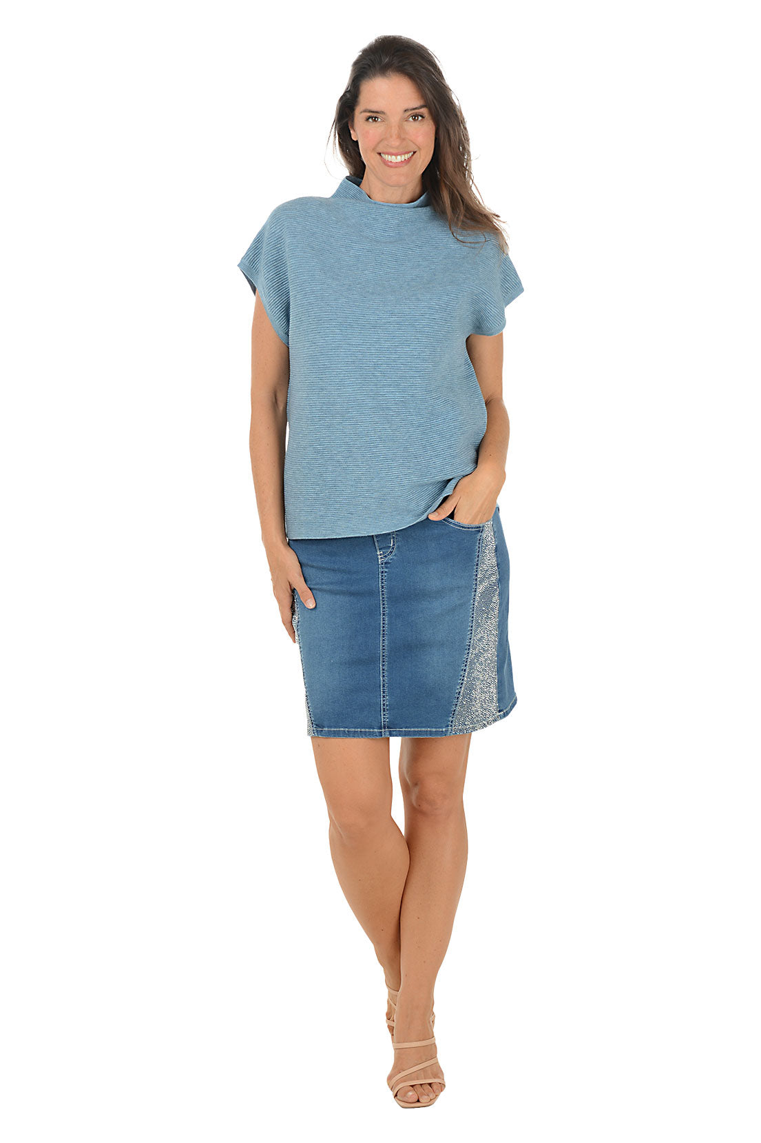 Woman wearing a blue top and denim skirt on a white background.