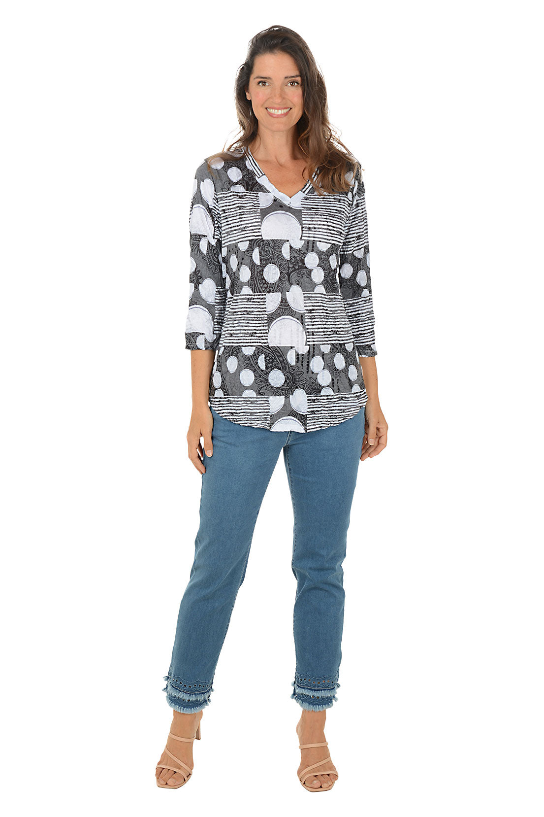 Woman wearing a patterned top and jeans on a white background.