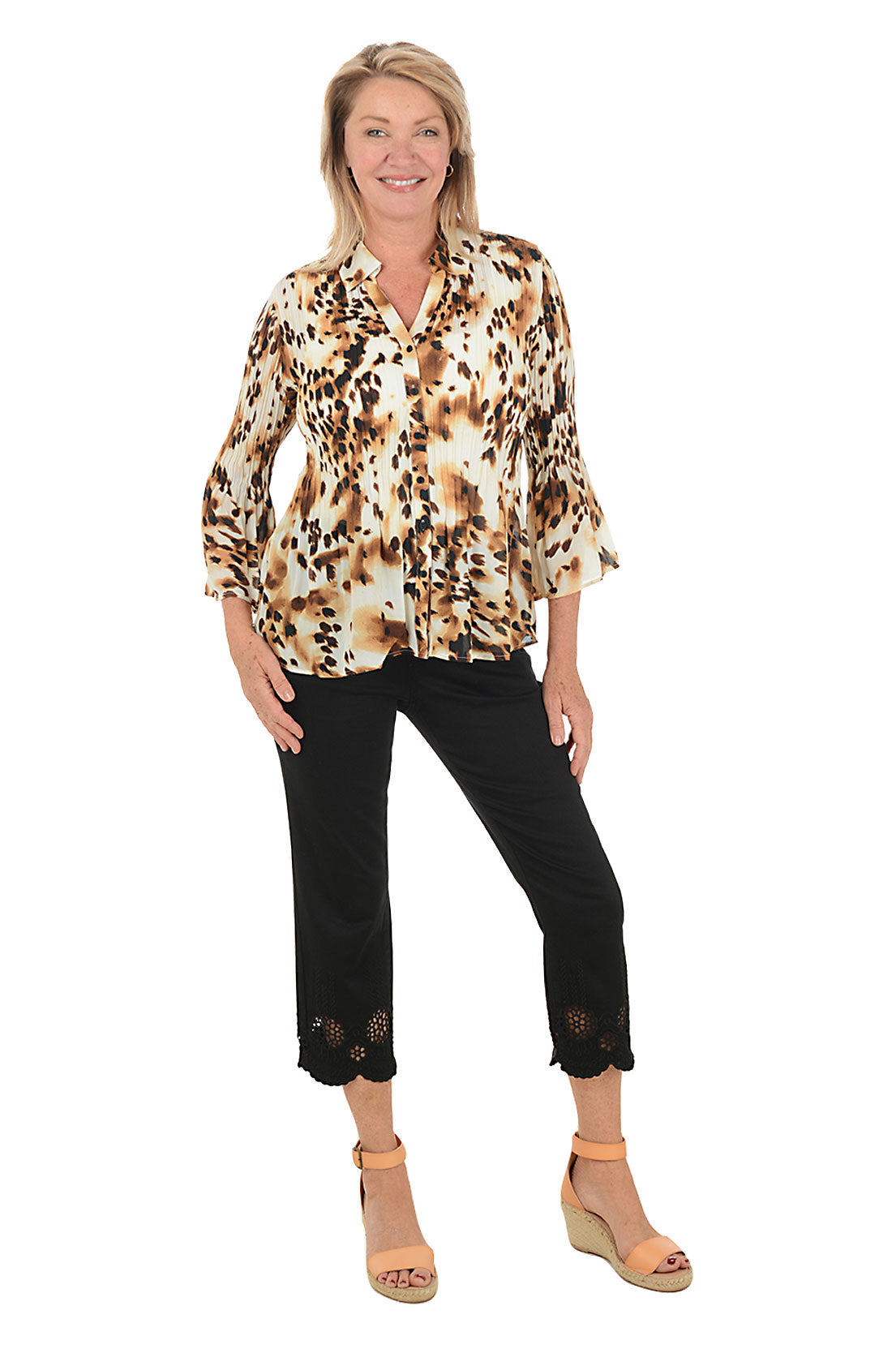 Woman wearing a patterned blouse and black pants on a white background