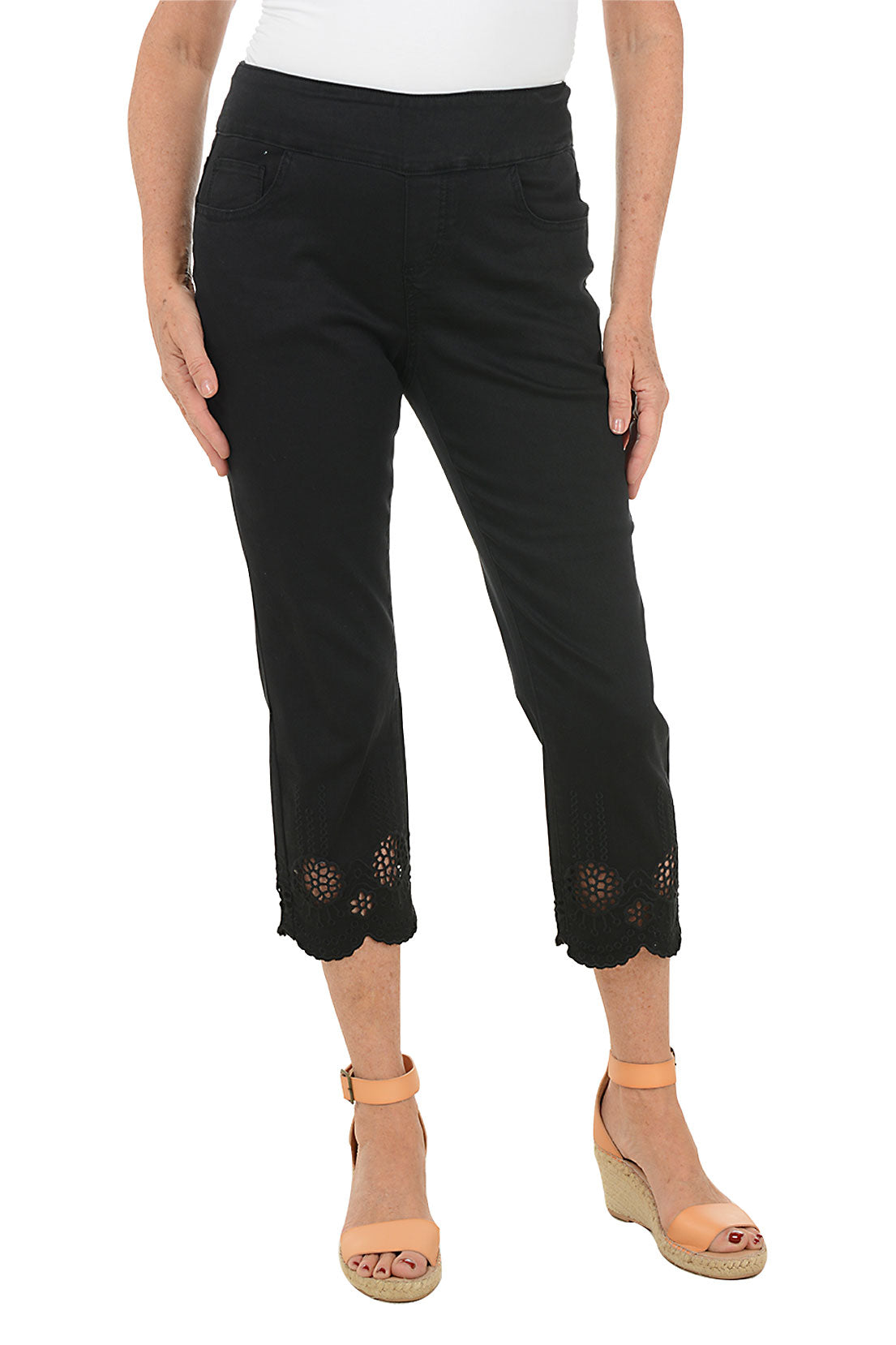Black pants with floral embroidery at the bottom worn by a person on a white background.