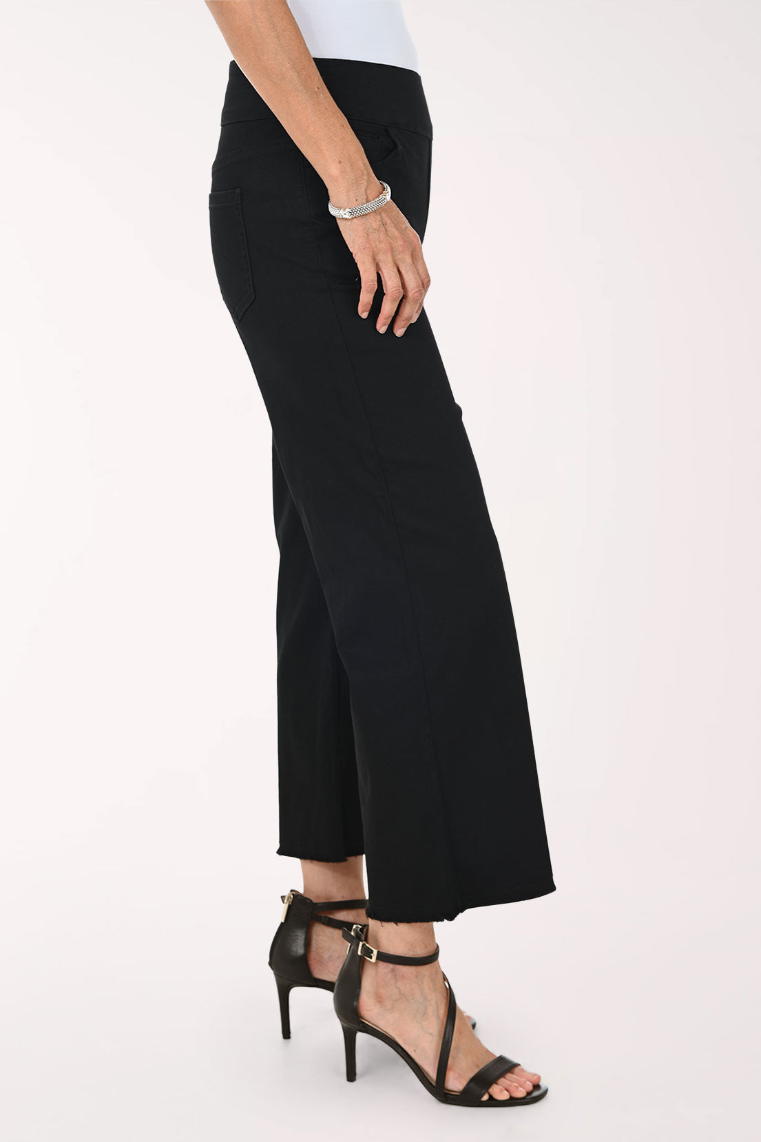 A model wearing black cropped wide-leg pants with a white top and black strappy high-heeled sandals, shown from the waist down against a plain light background.