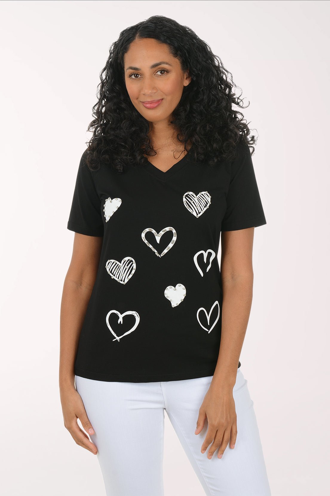 Woman wearing a black t-shirt with white heart patterns on a plain background