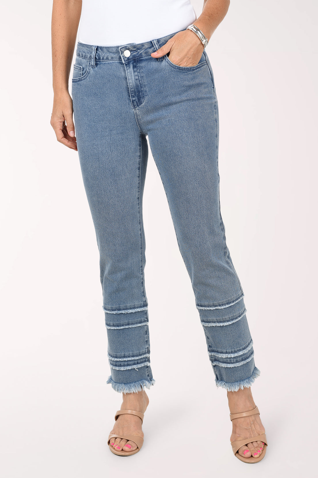 Front view of the light-wash frayed tiered denim pants showing the five-pocket styling and frayed tiers at both ankles.