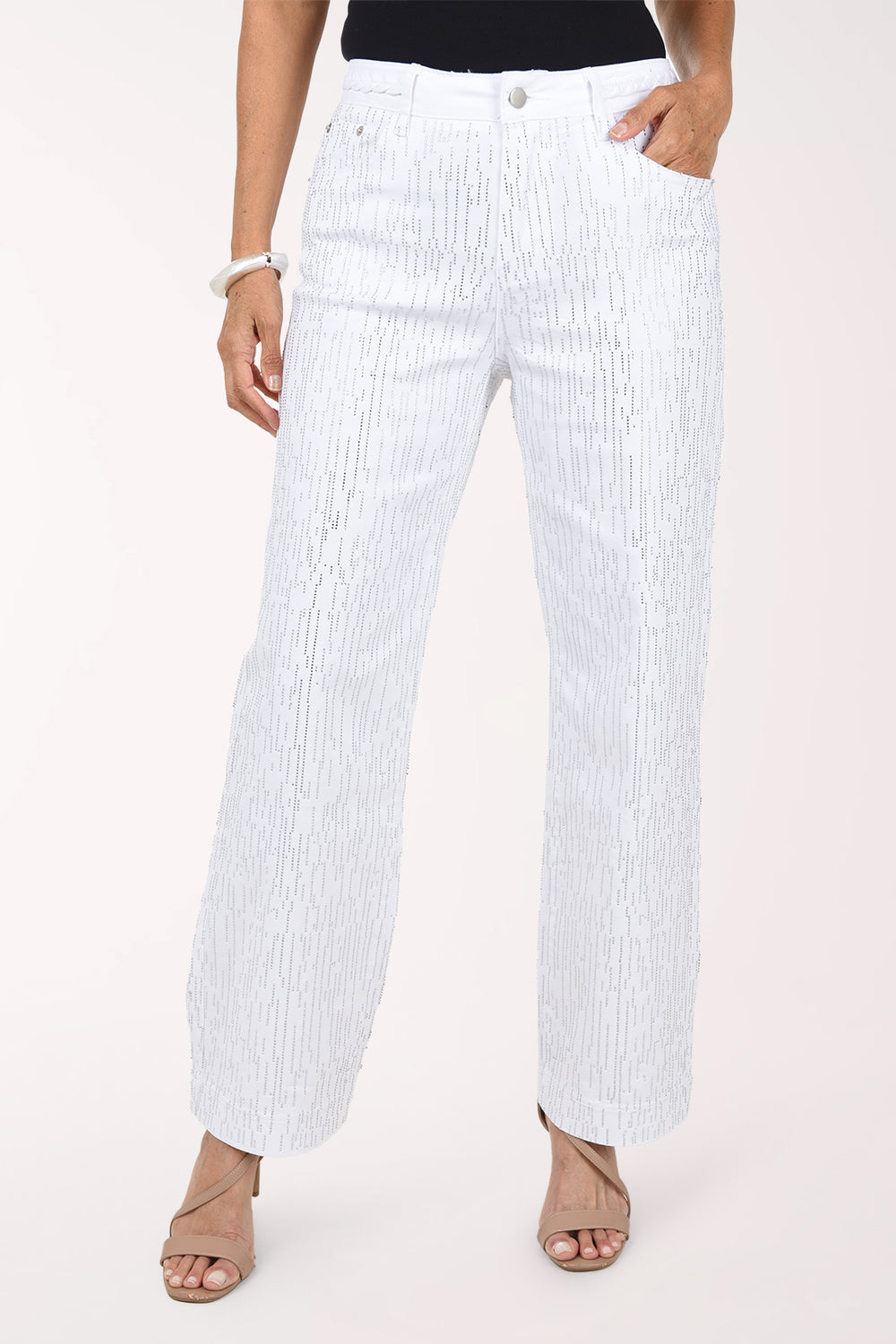 Front view of white stretch denim wide leg pants covered in fine vertical rows of silver rhinestones, with five-pocket styling, worn with a black top and nude heeled sandals.