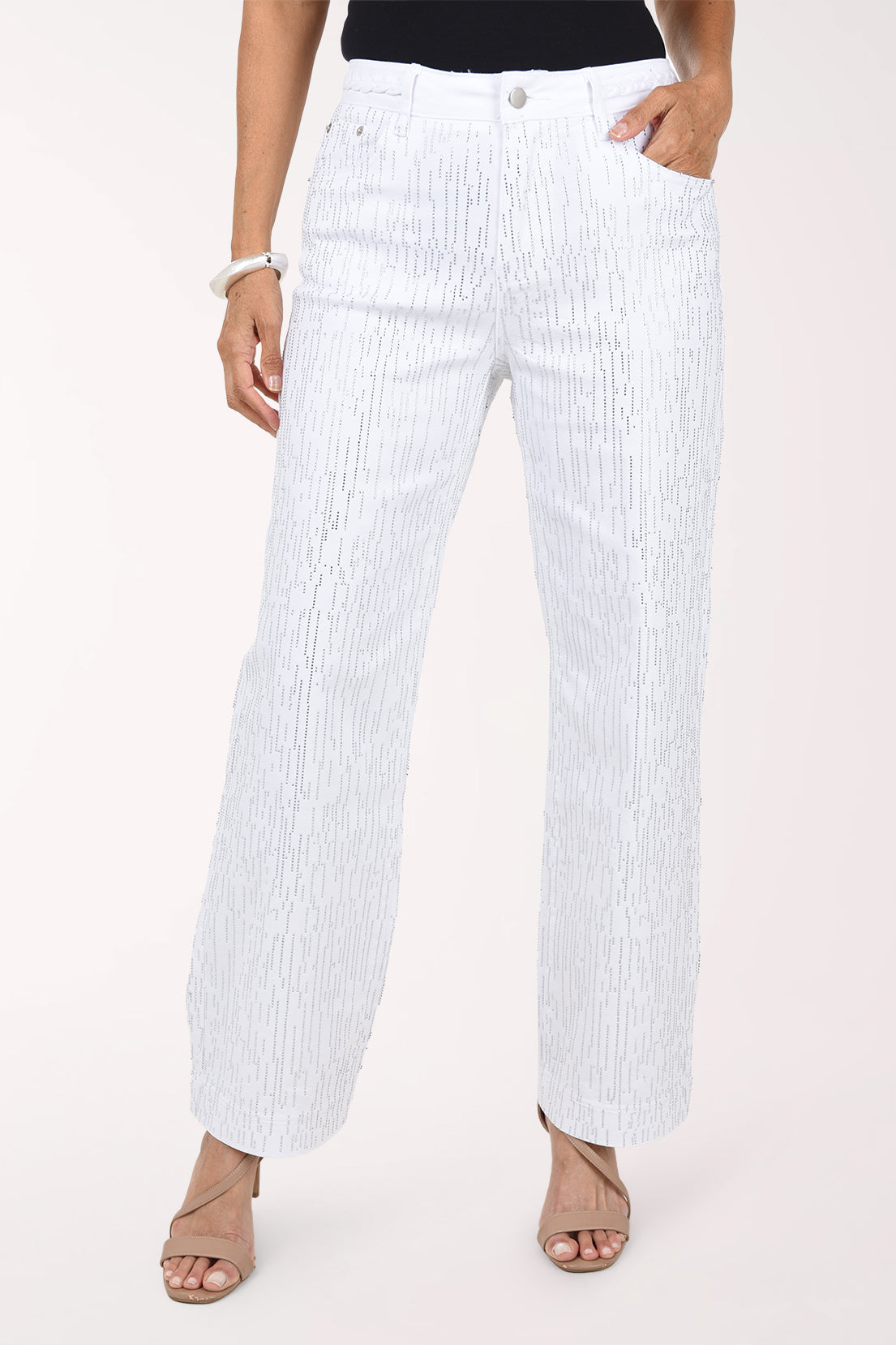 Front view of white stretch denim wide leg pants covered in fine vertical rows of silver rhinestones, with five-pocket styling, worn with a black top and nude heeled sandals.