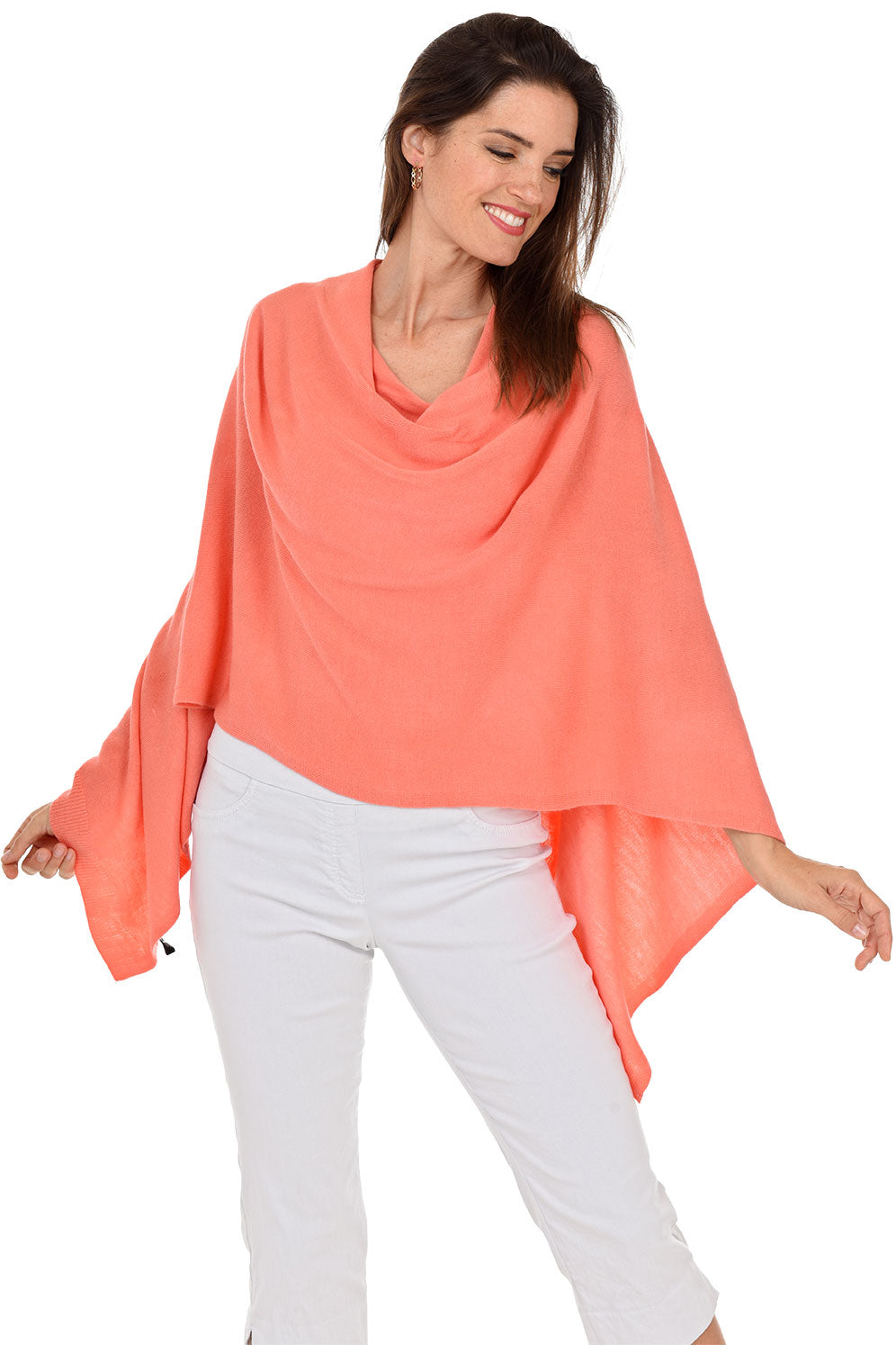 A woman wearing a coral popover poncho with white pants.