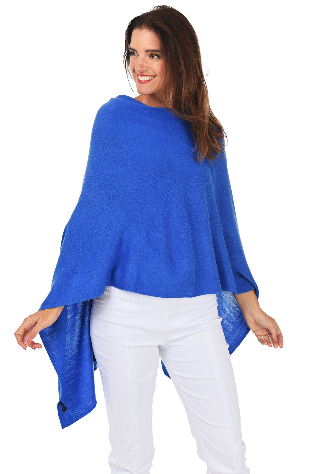 A woman wearing a royal blue popover poncho with white pants.