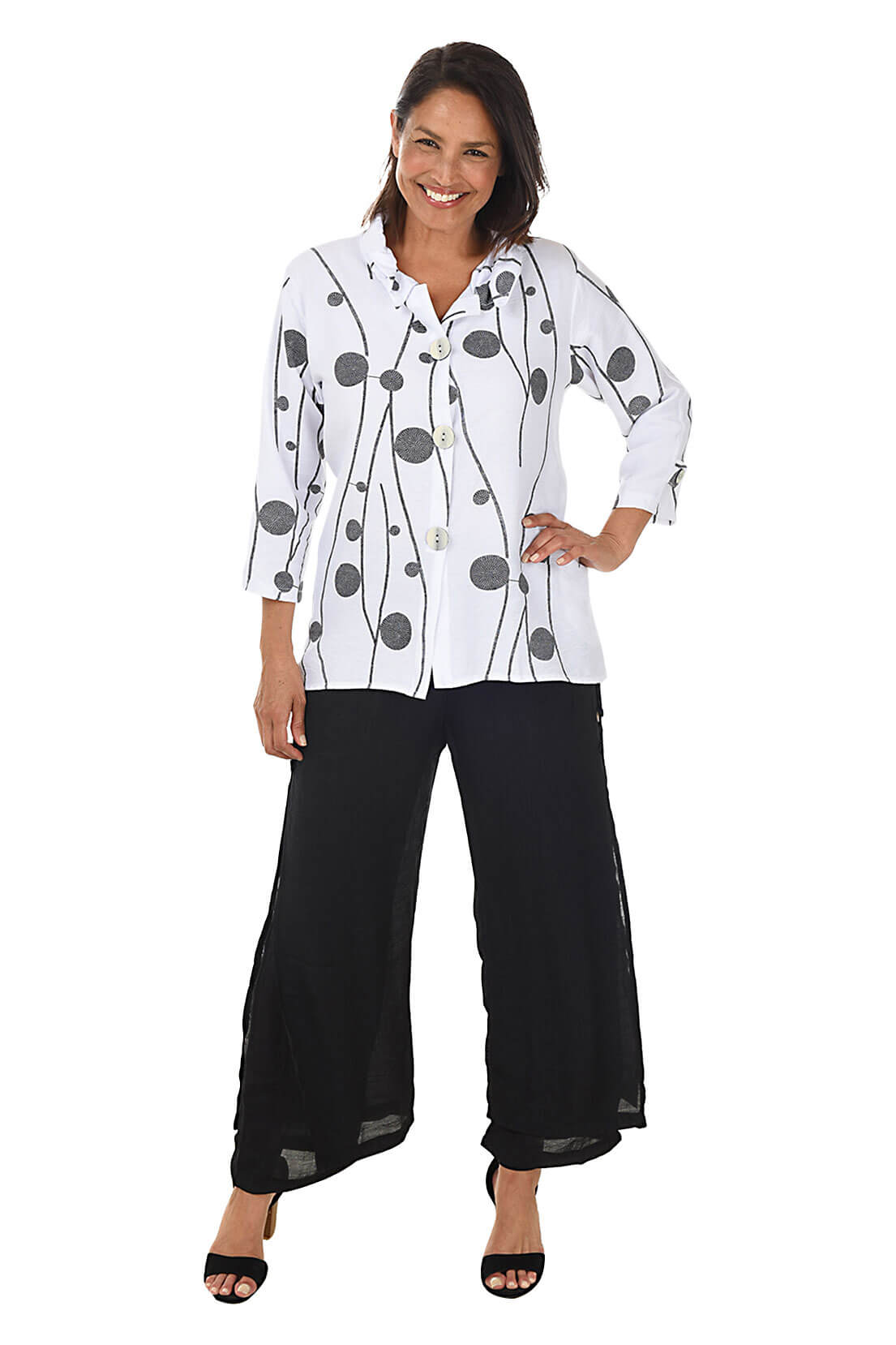 Woman wearing a white blouse with black polka dots and black pants on a white background