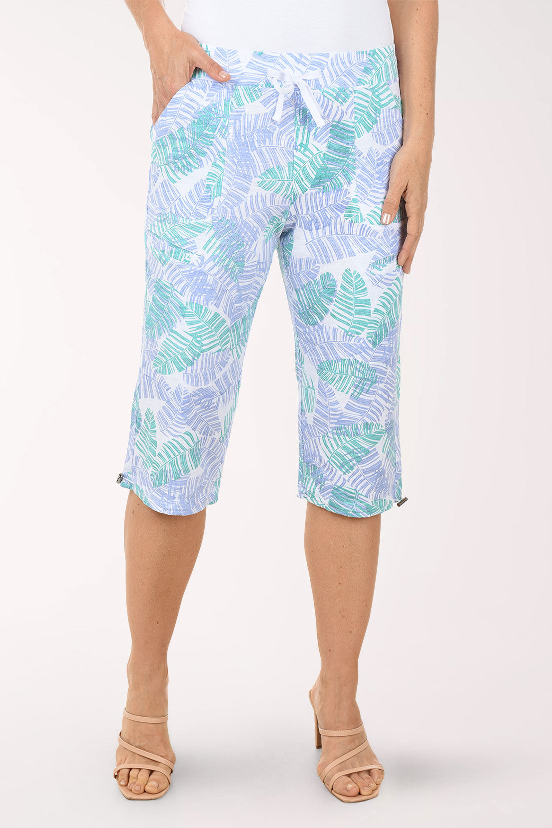 Person wearing light blue capri pants with a leaf pattern on a white background