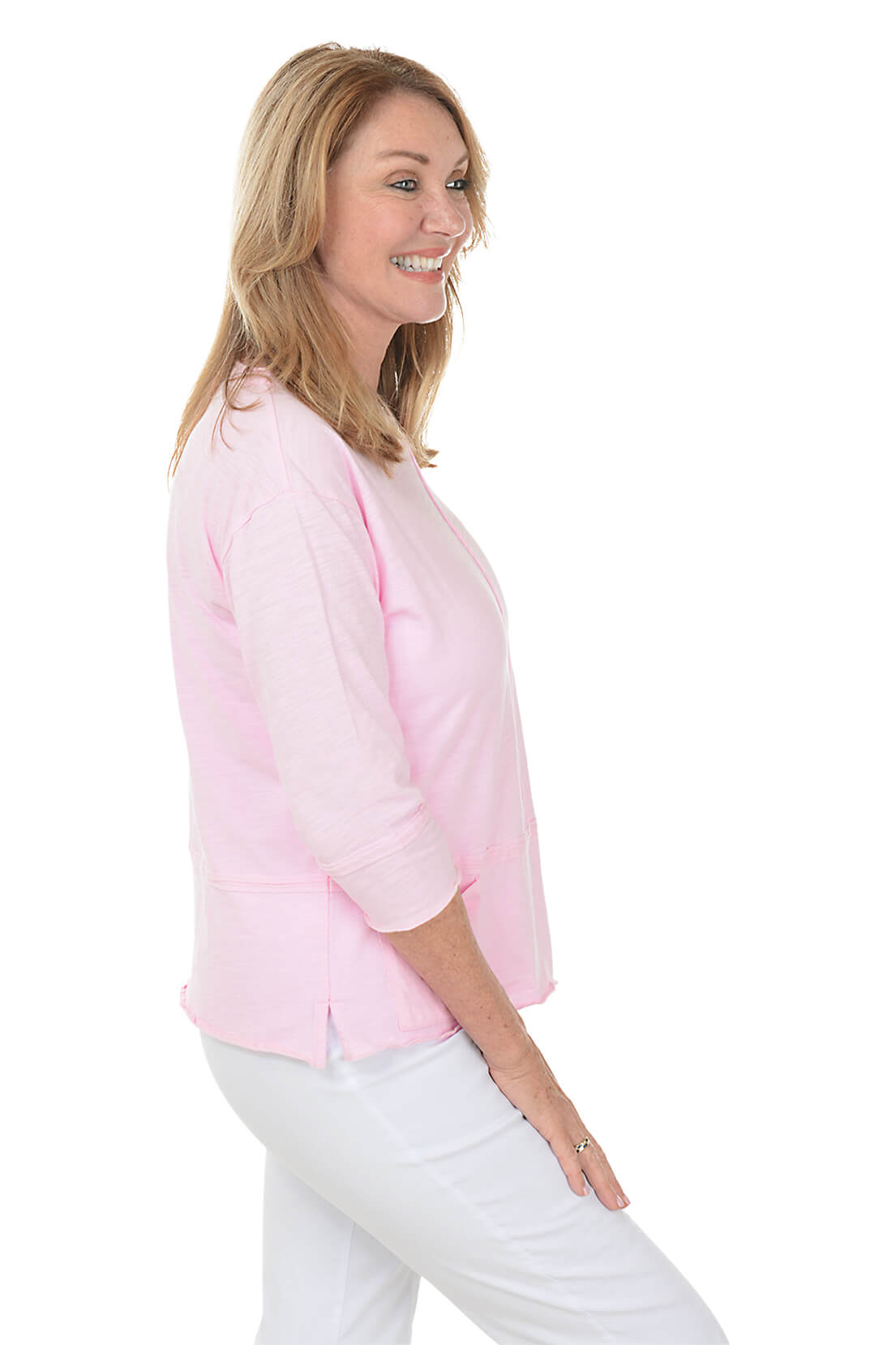 Woman wearing a pink blouse and white pants on a white background. Side shot.