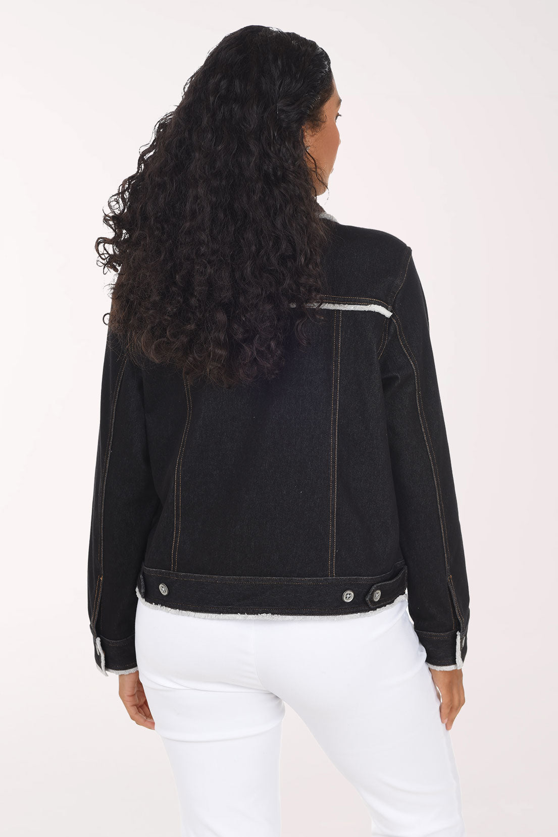 Woman wearing a black denim button down jacket with contrast stitching and fringing