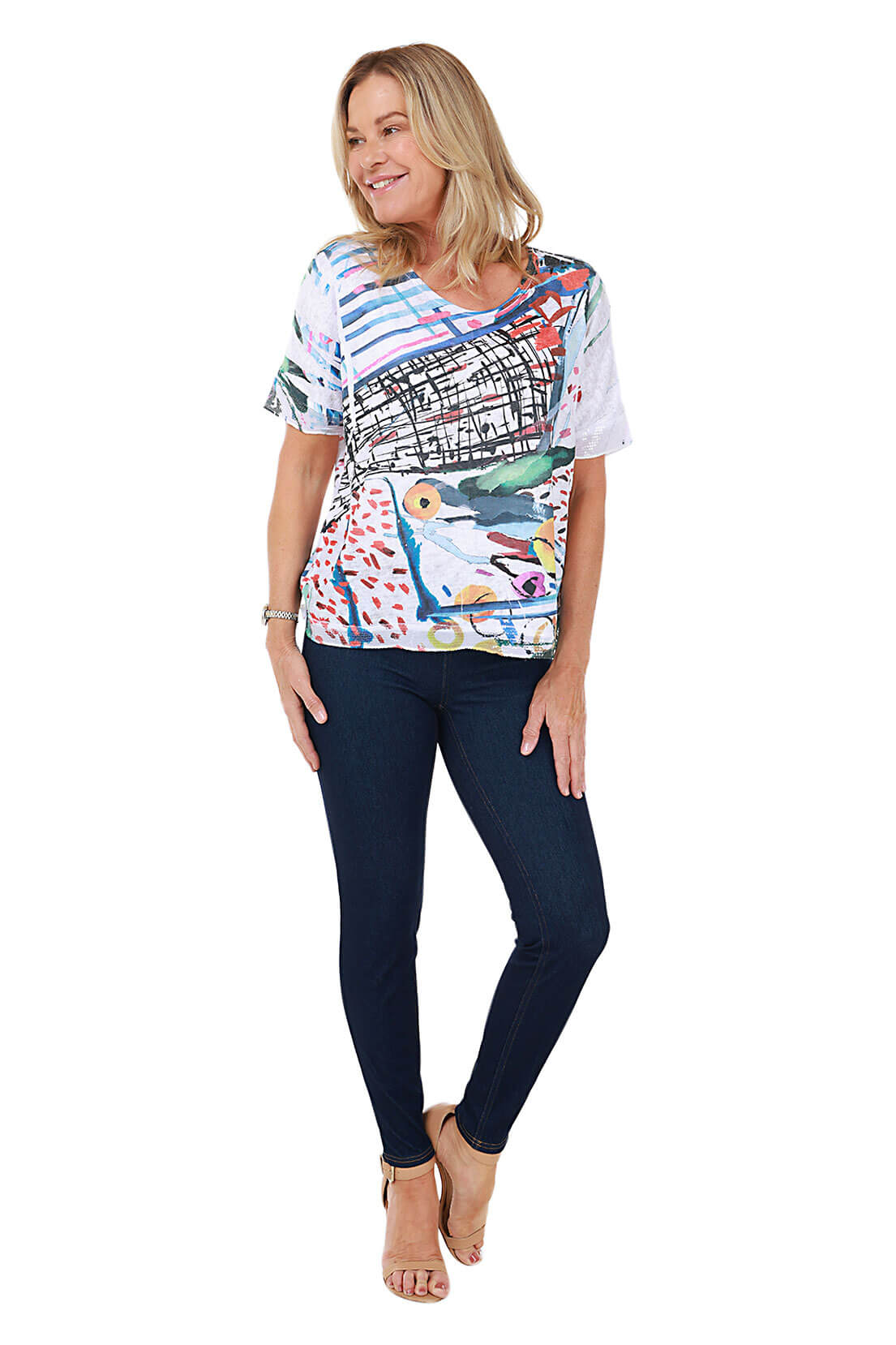 Woman wearing a colorful top and dark jeans on a white background