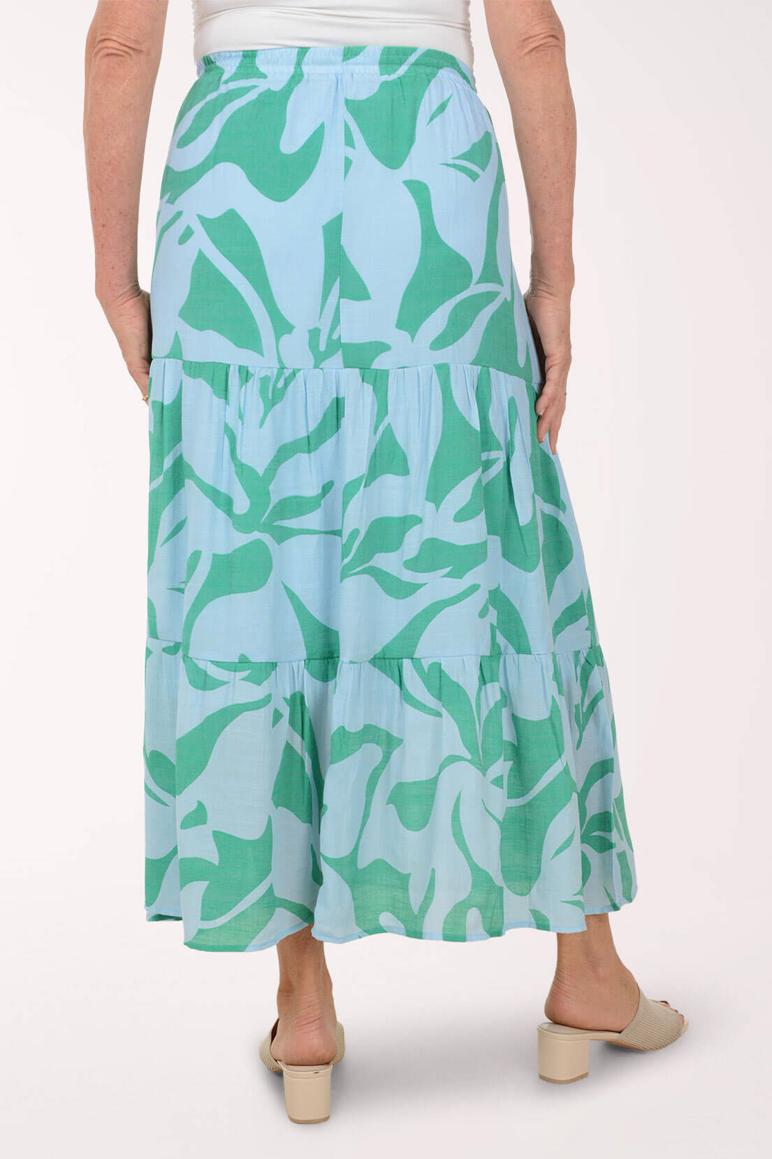 Person wearing a green and blue leaf-patterned skirt on a white background
