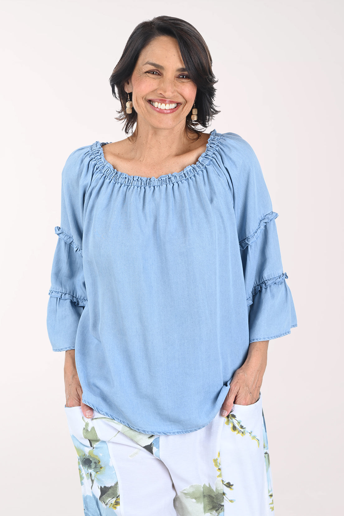 Woman wearing a light blue blouse with ruffled sleeves on a white background