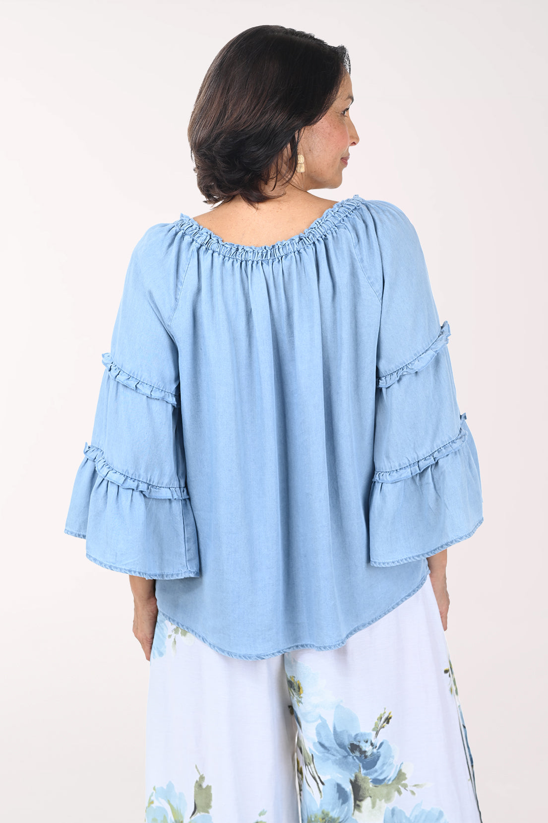 Woman wearing a light blue blouse with ruffled sleeves on a white background