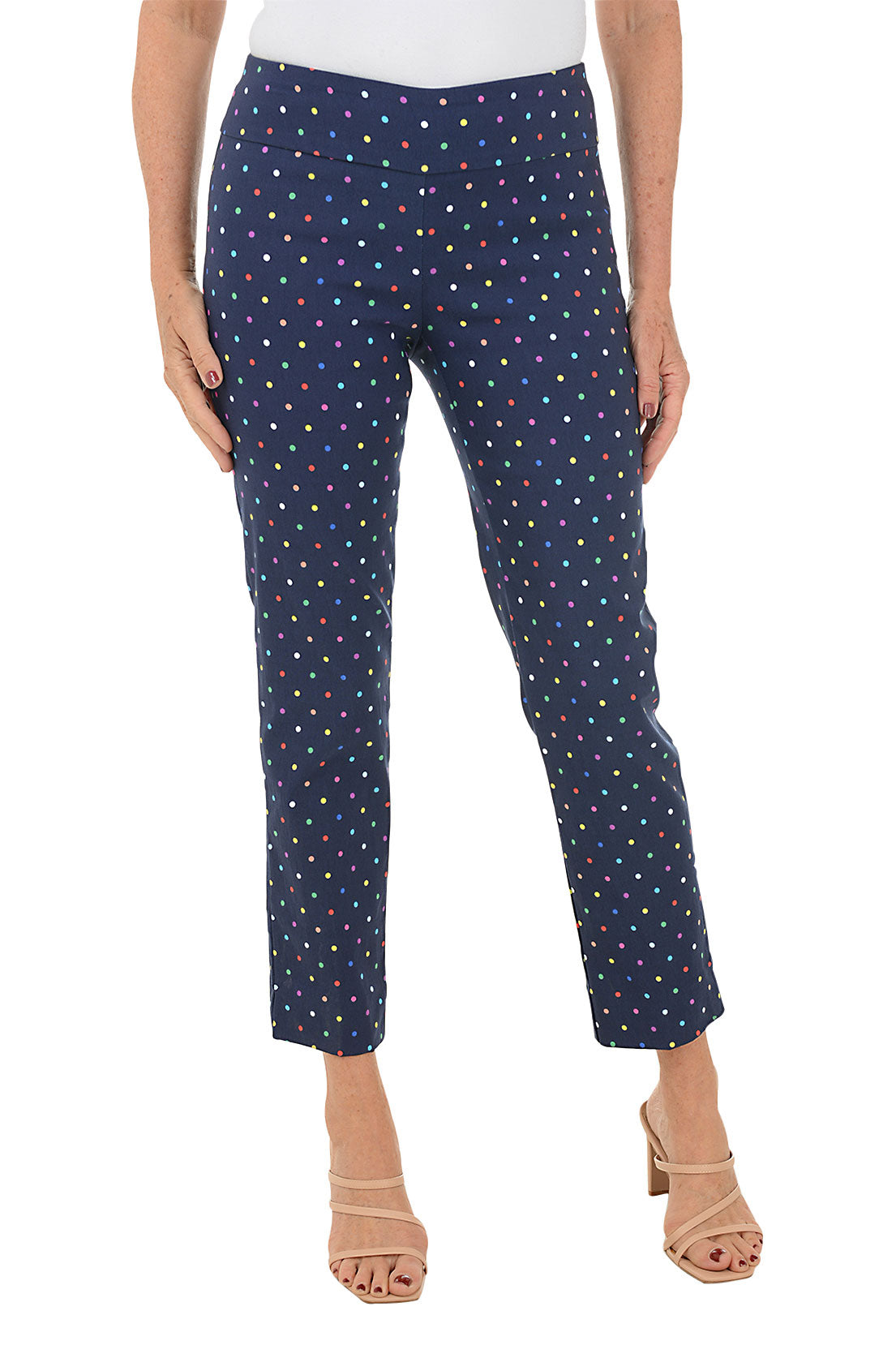 A front shot of a model wearing navy pull-on ankle pants with a multicolor dot pattern, standing heel to heel.