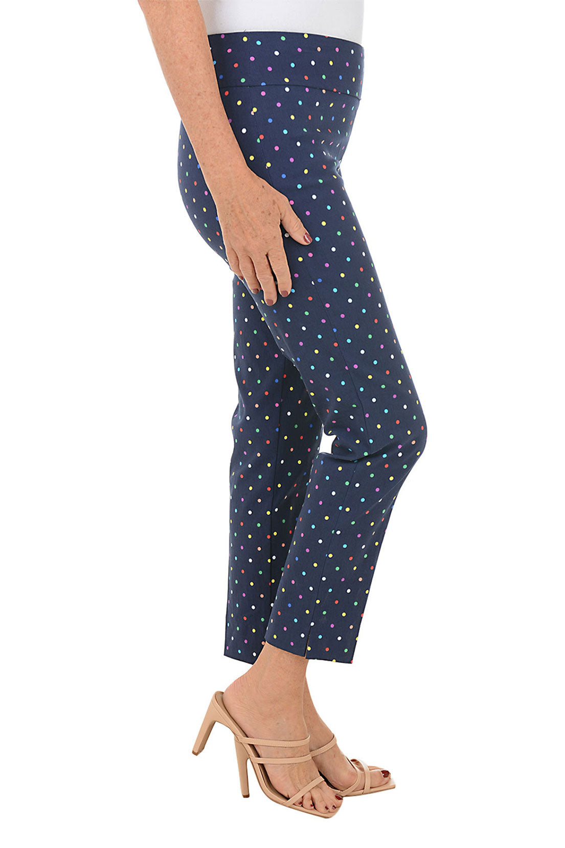 A side shot of a model wearing navy pull-on ankle pants with a multicolor dot pattern.