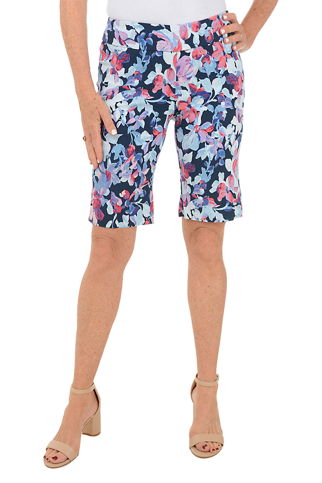 A front shot of a model wearing a pair of pull-on bermuda shorts with a floral pattern, featuring a flat front and back, side slits, and a mid-rise waist.
