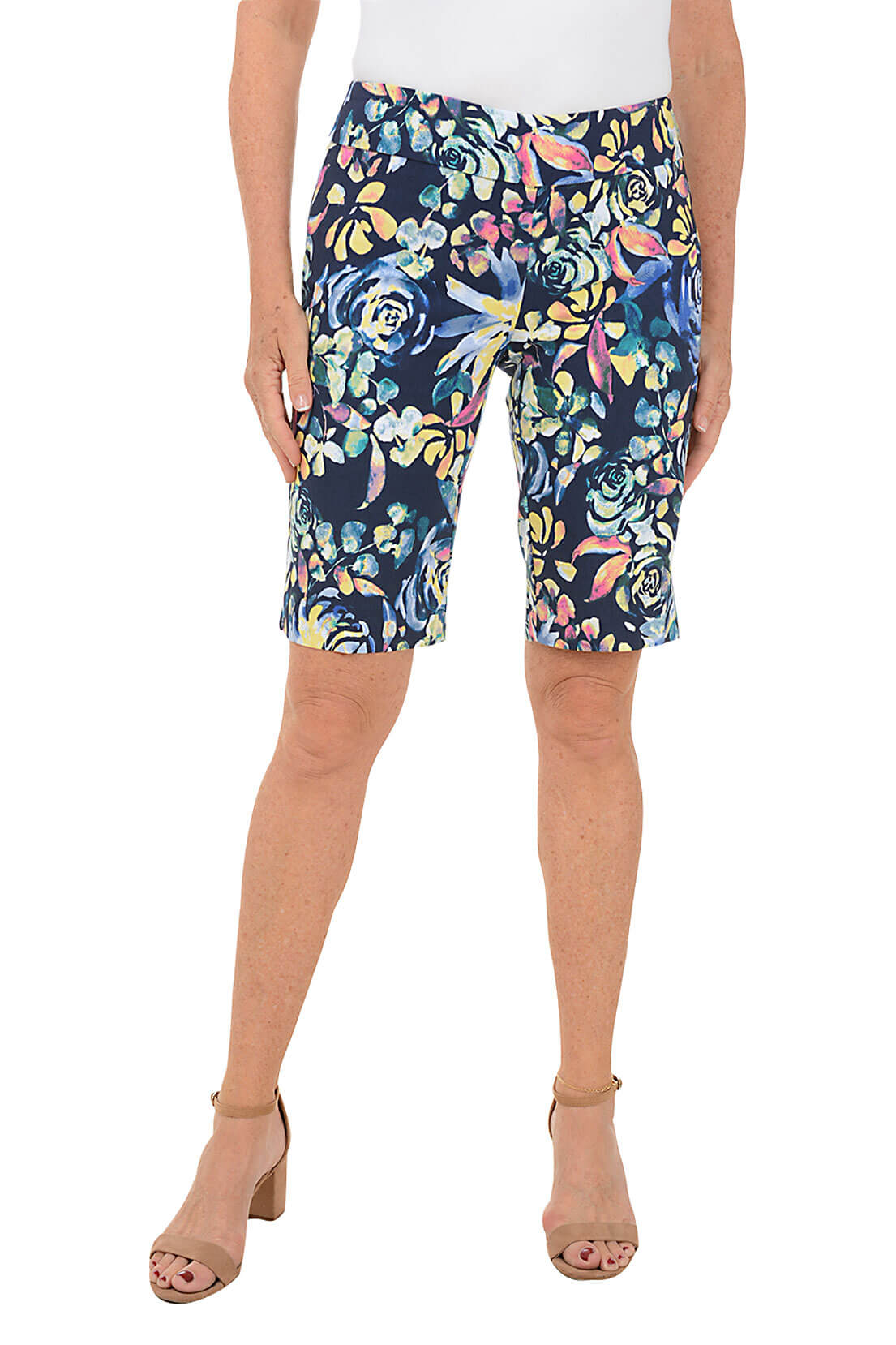 A front shot of a model wearing a pair of Bermuda shorts with a floral pattern, featuring a flat front and back, an elastic waistband, and a side slit at the hemline.