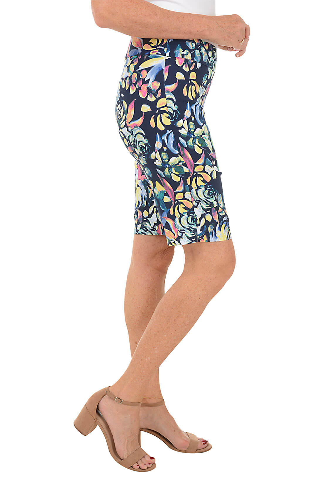 A side shot of a model wearing a pair of Bermuda shorts with a floral pattern, featuring a flat front and back, an elastic waistband, and a side slit at the hemline.