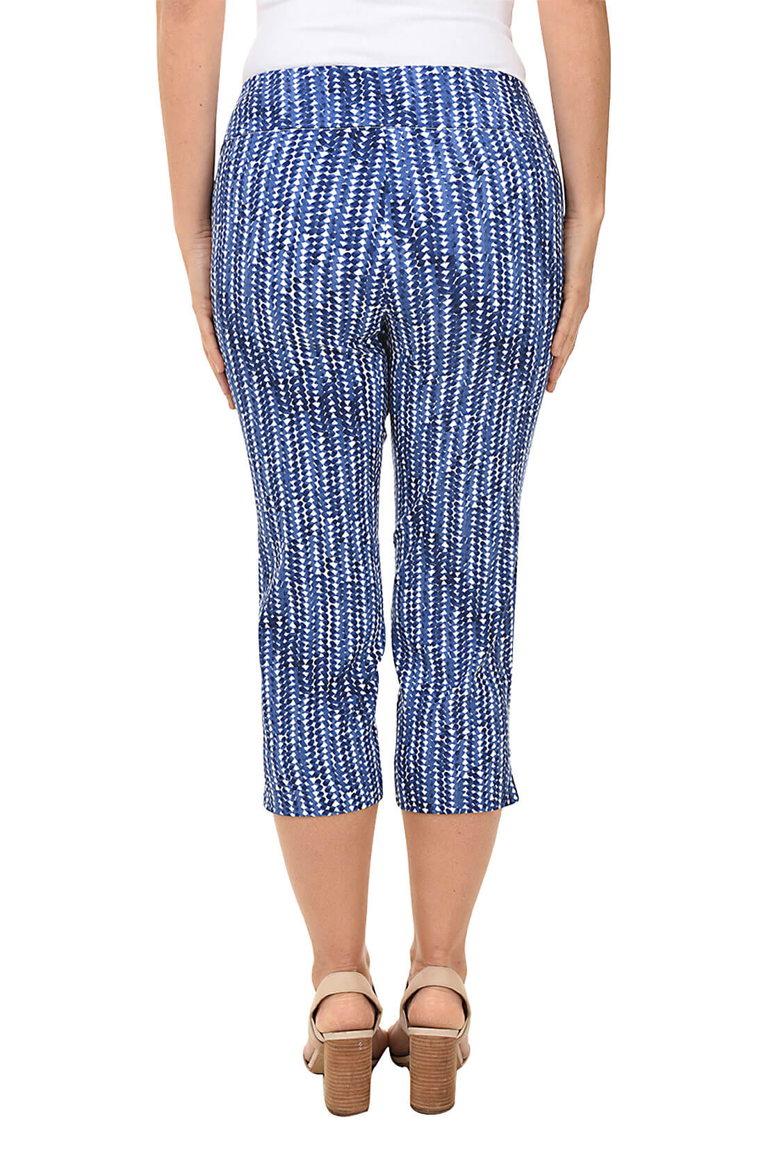 A back shot of a model wearing a pair of blue striped pull-on crop pants with an elastic waistband and a side slit on the hemline.